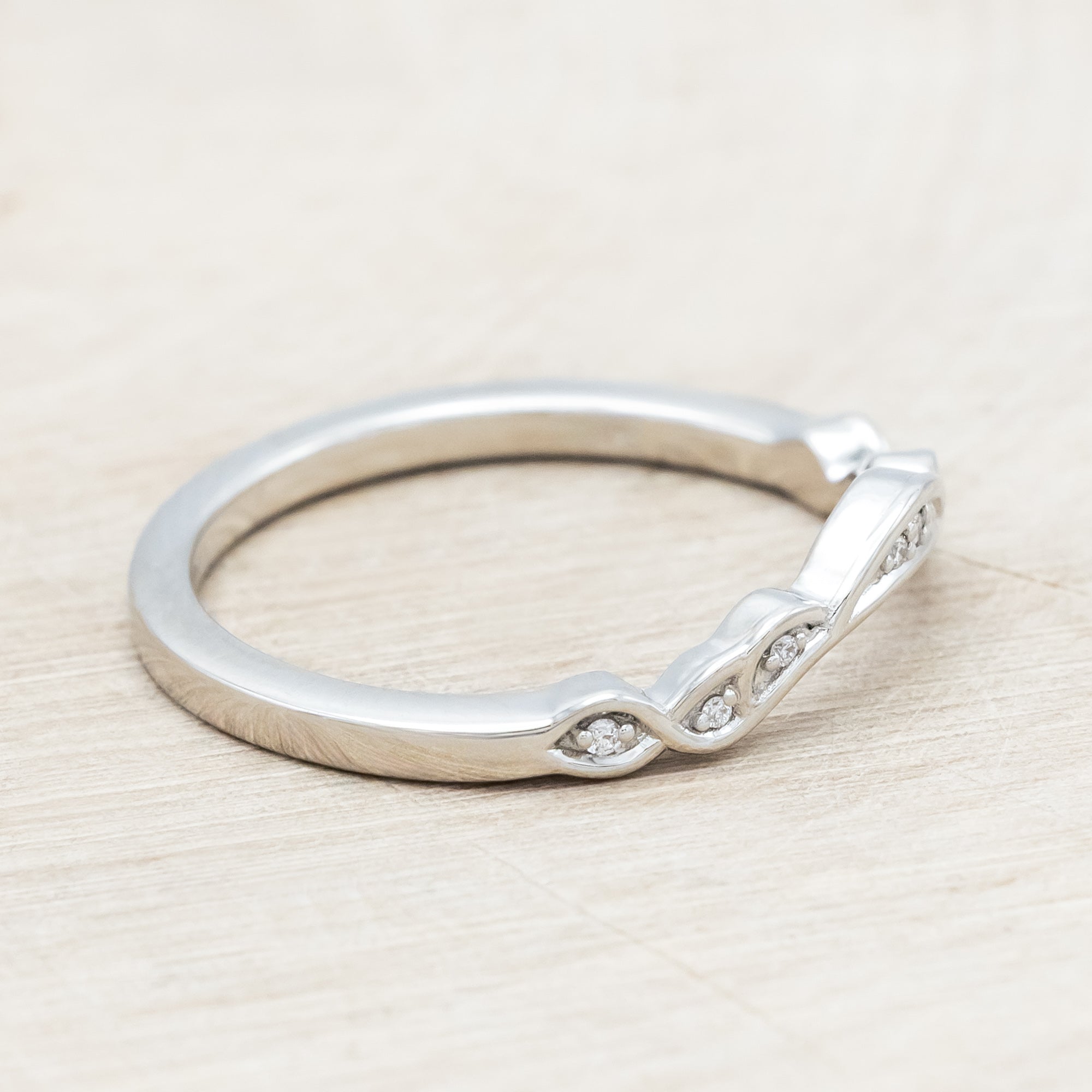 14K white gold ring with diamond accents on a wooden surface