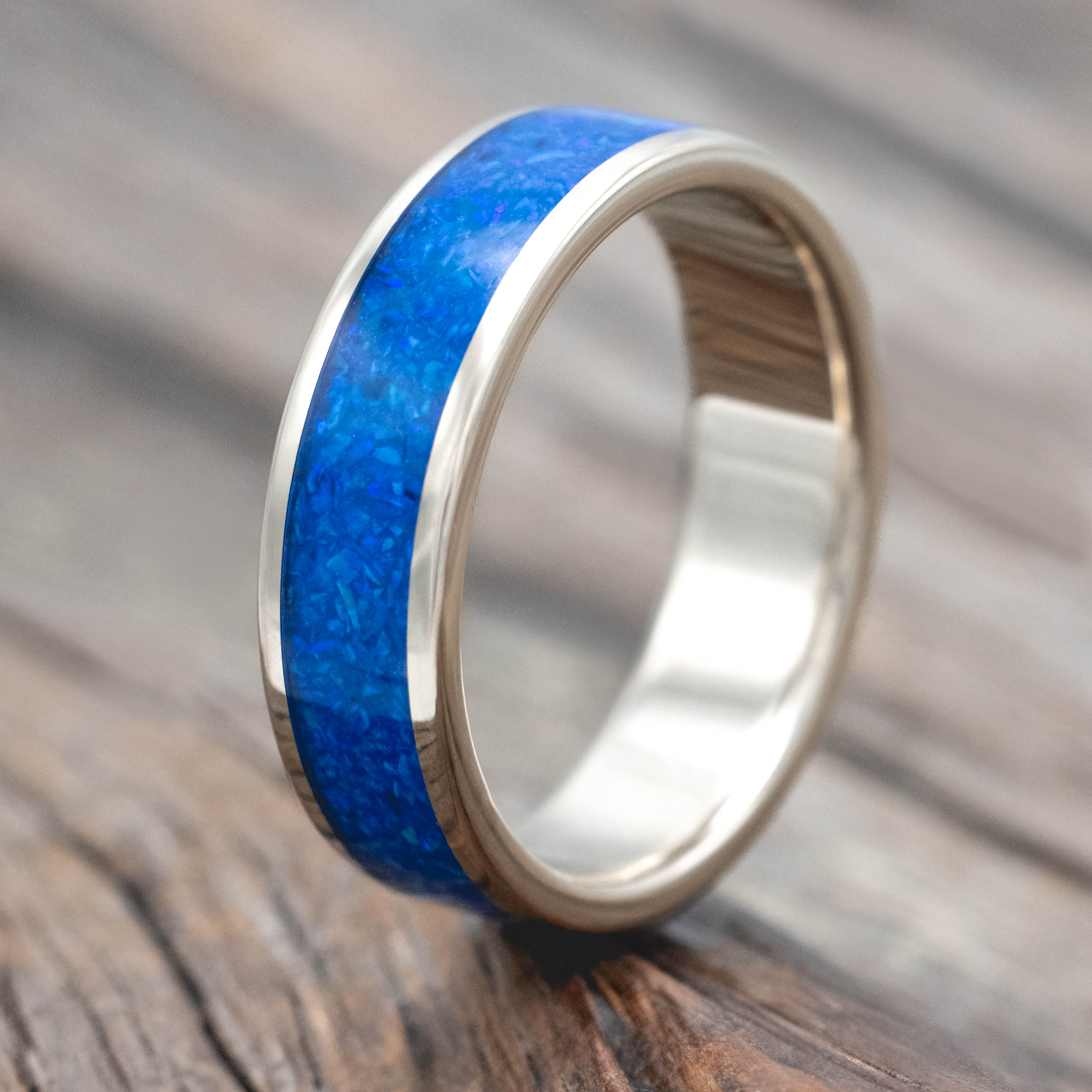 14K white gold ring with blue opal inlay on a wooden surface