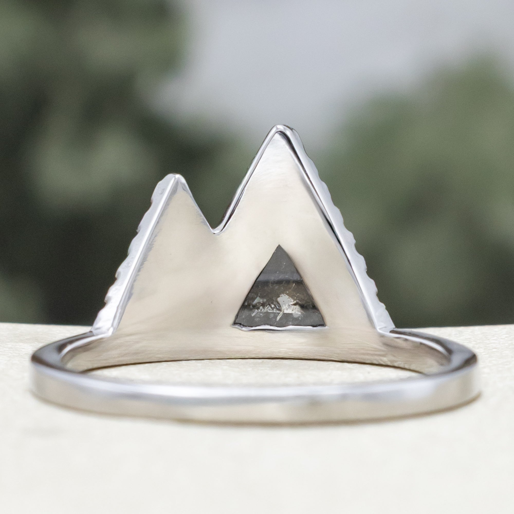 White gold ring with salt & pepper diamond center stone and diamond accents on a blurred background