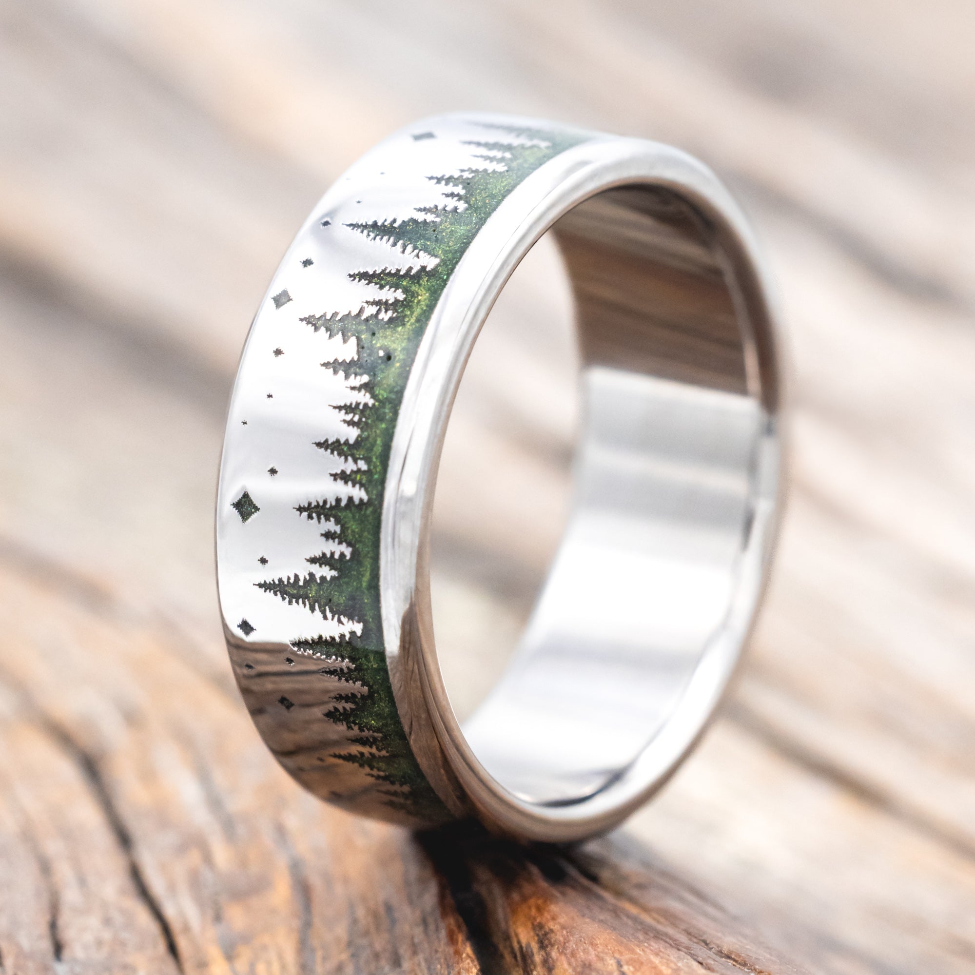 Ring with mountain and forest design with green mica powder on a wooden surface