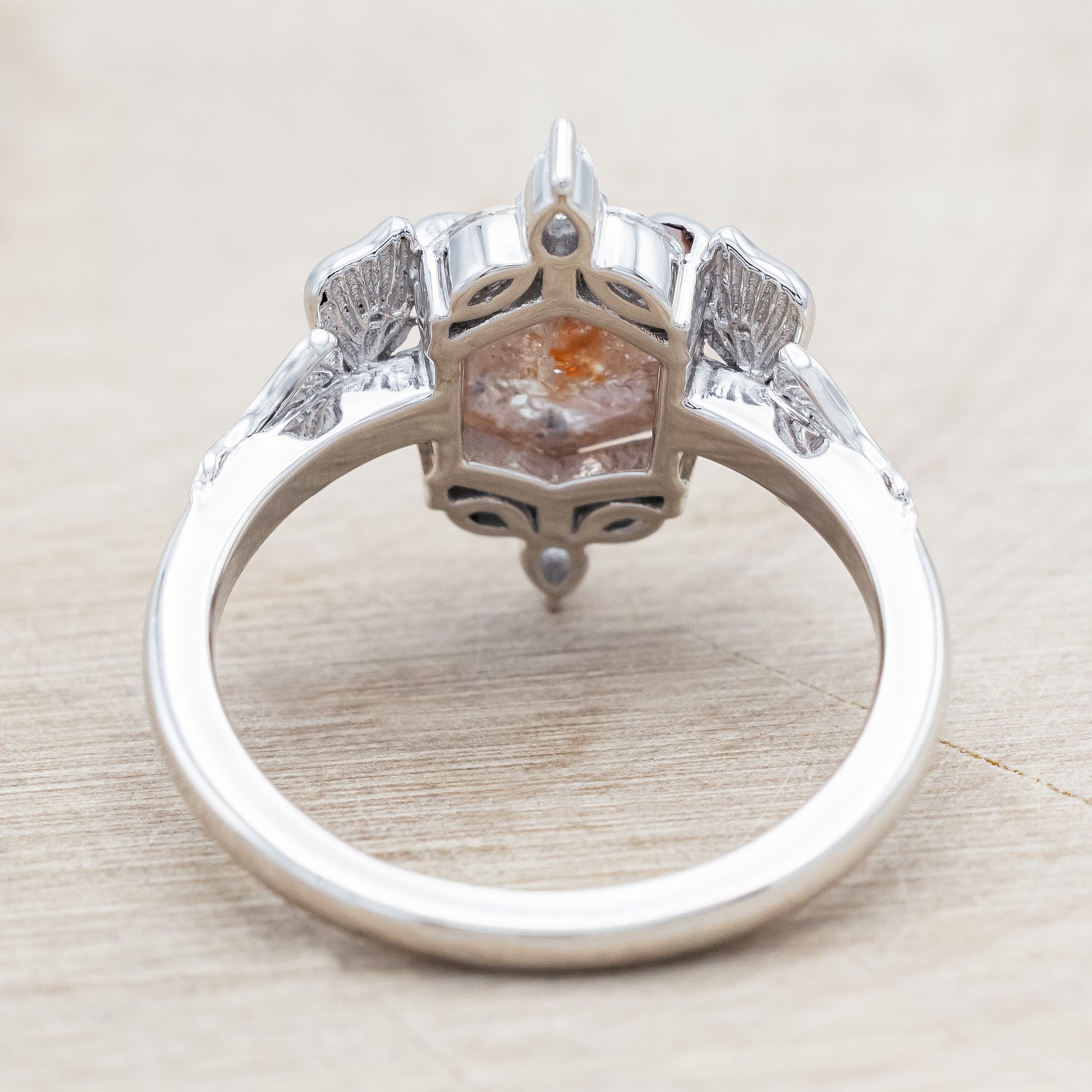 White gold ring with a salt & pepper diamond and moth design on a beige background