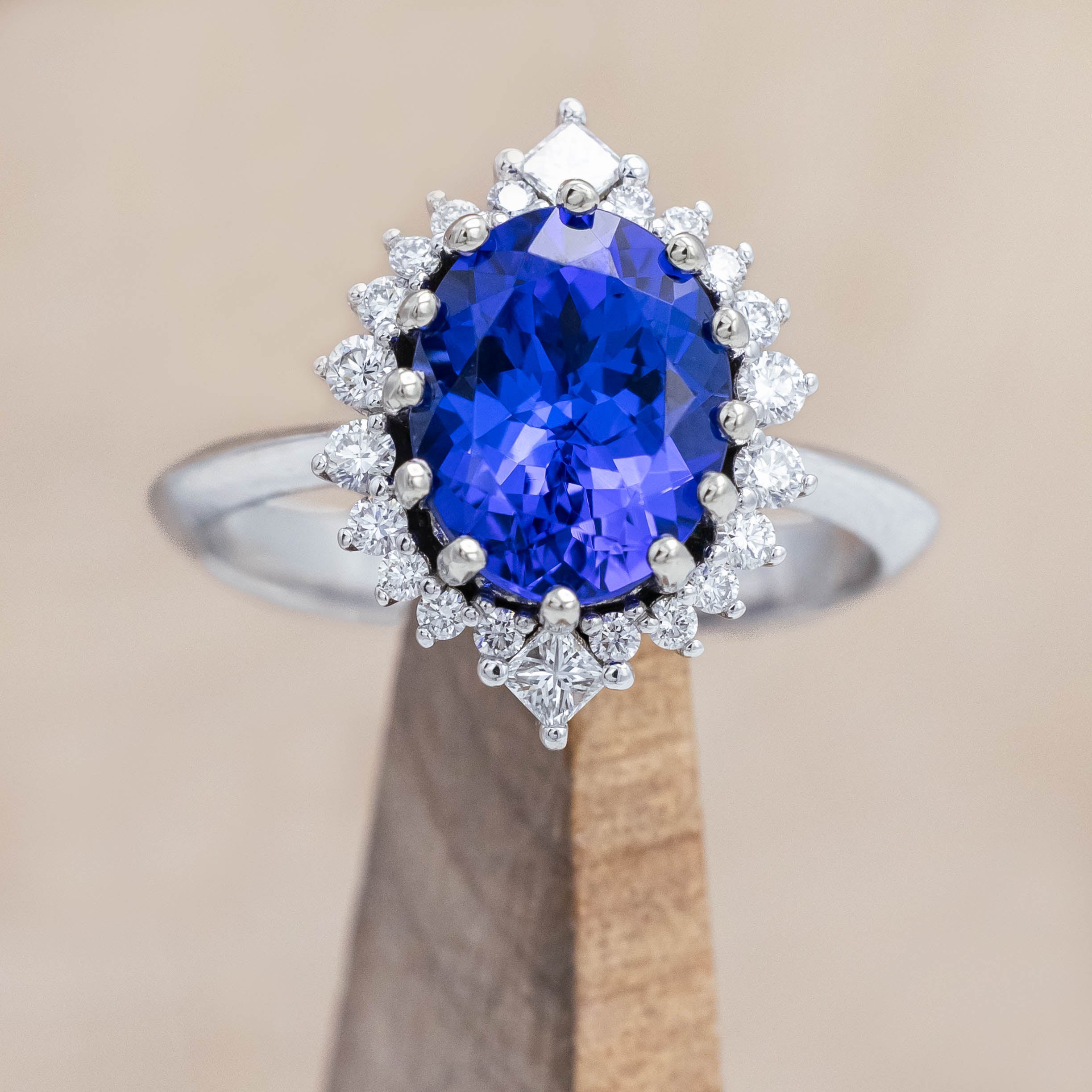 14K white gold ring with a blue tanzanite center stone and diamond halo on a beige background