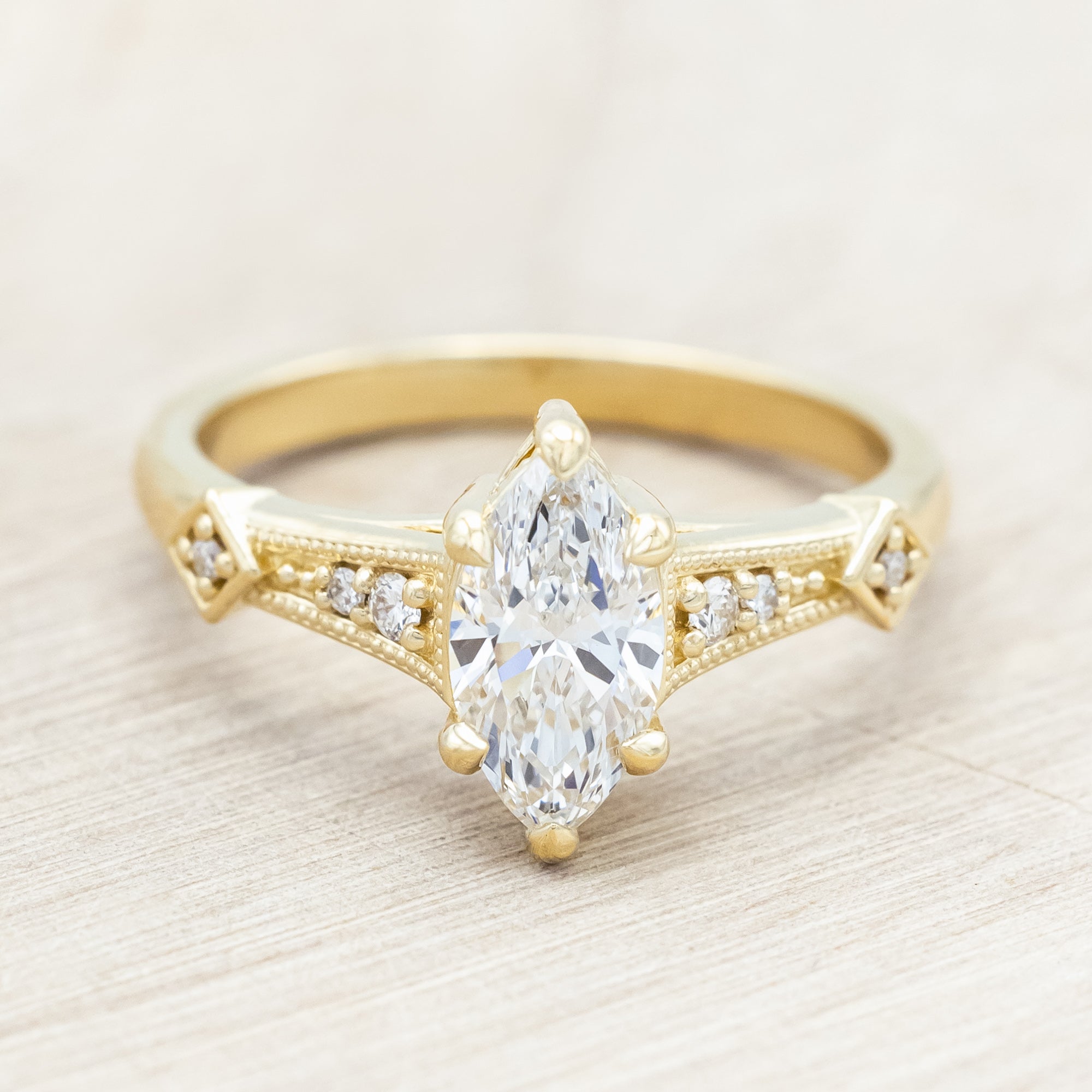 14K gold ring with lab-grown diamond center stone & accents on a light wooden background