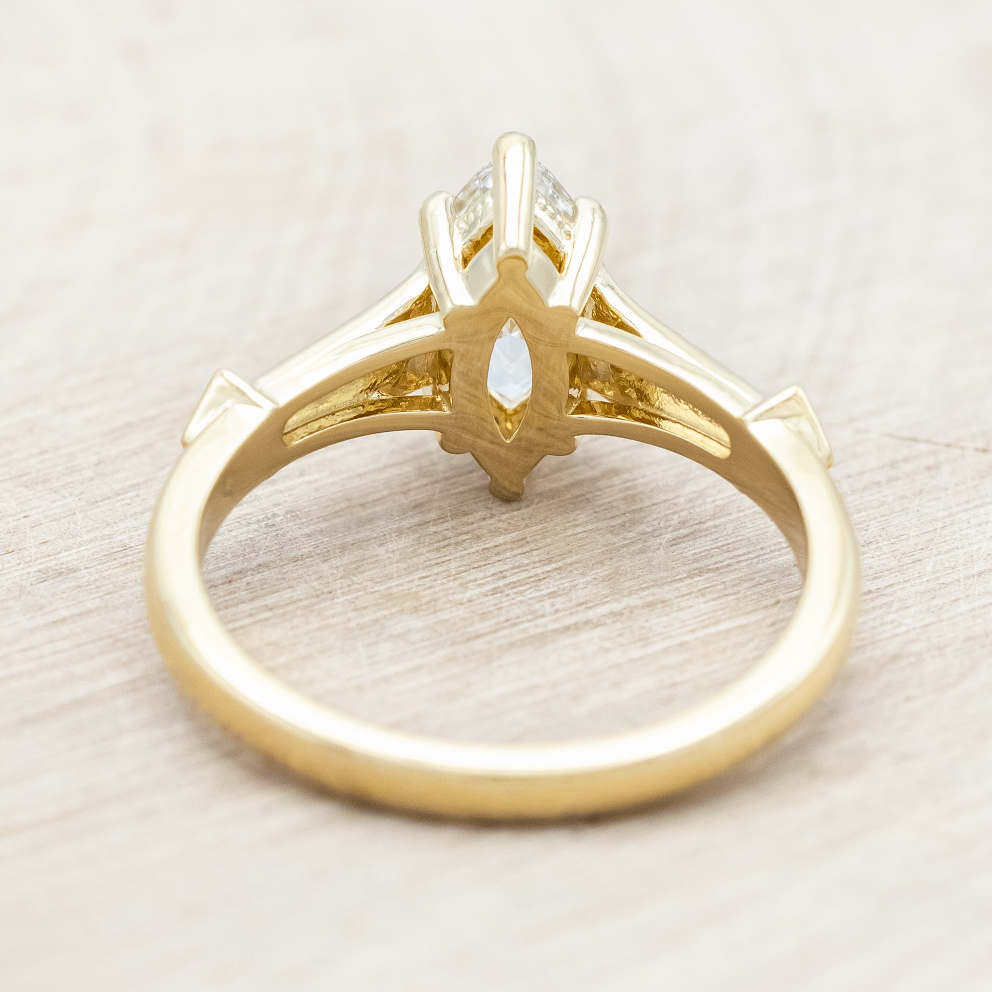 14K gold ring with lab-grown diamond center stone & accents on a light wooden background