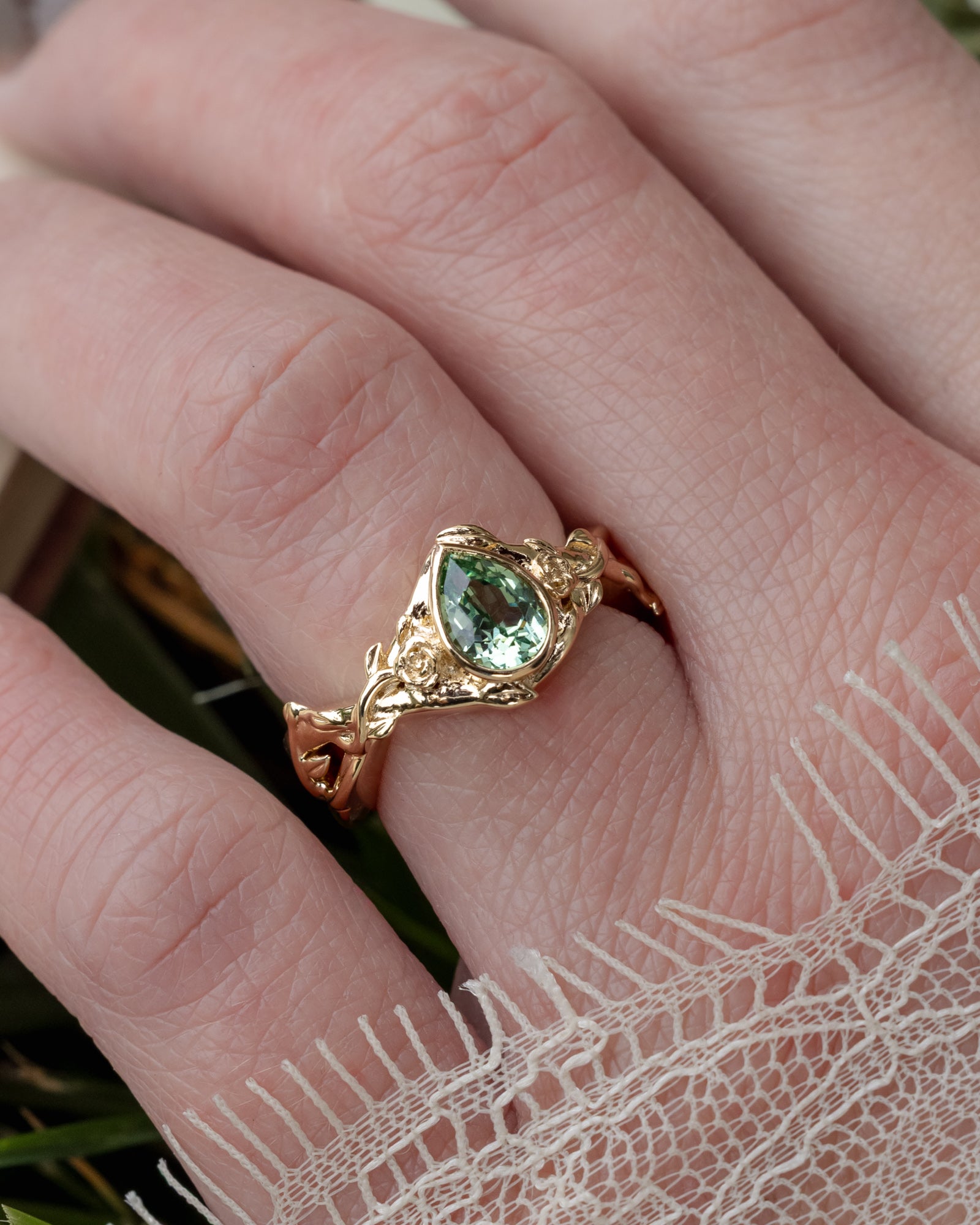 Hand wearing rold ring with sapphire with a lace sleeve.