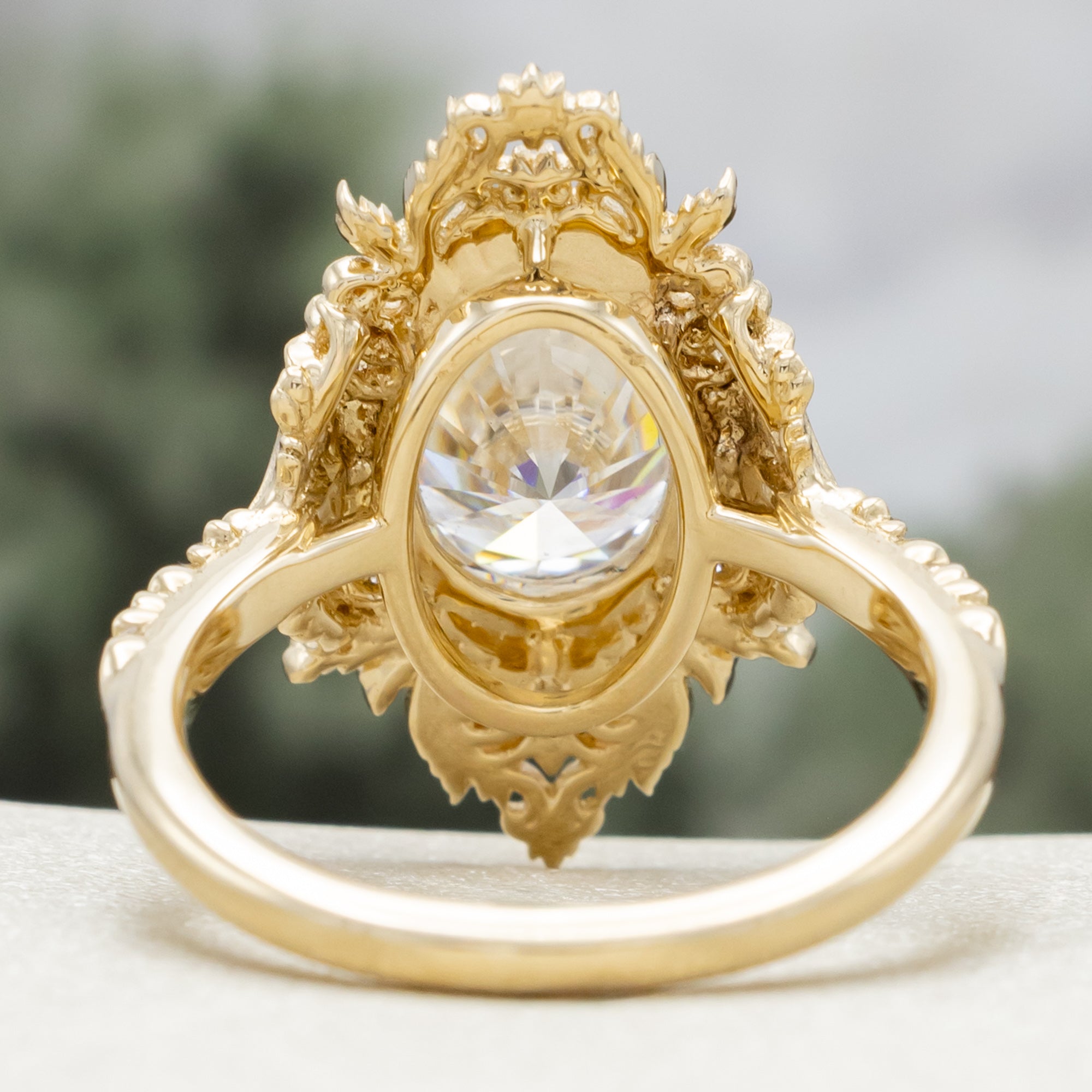 Gold ring with a large moissanite and intricate filigree on a neutral background