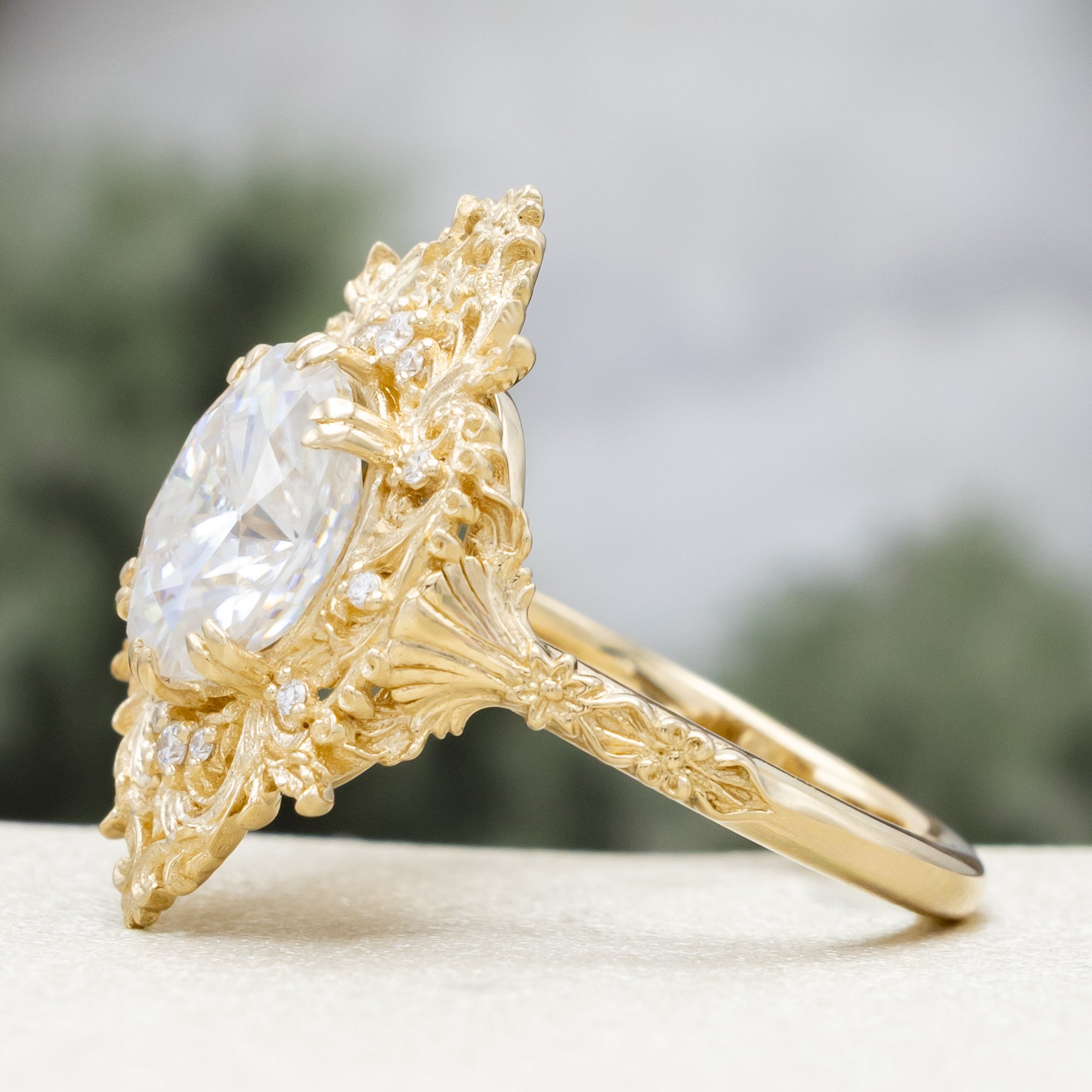 Gold ring with a large moissanite and intricate filigree on a neutral background