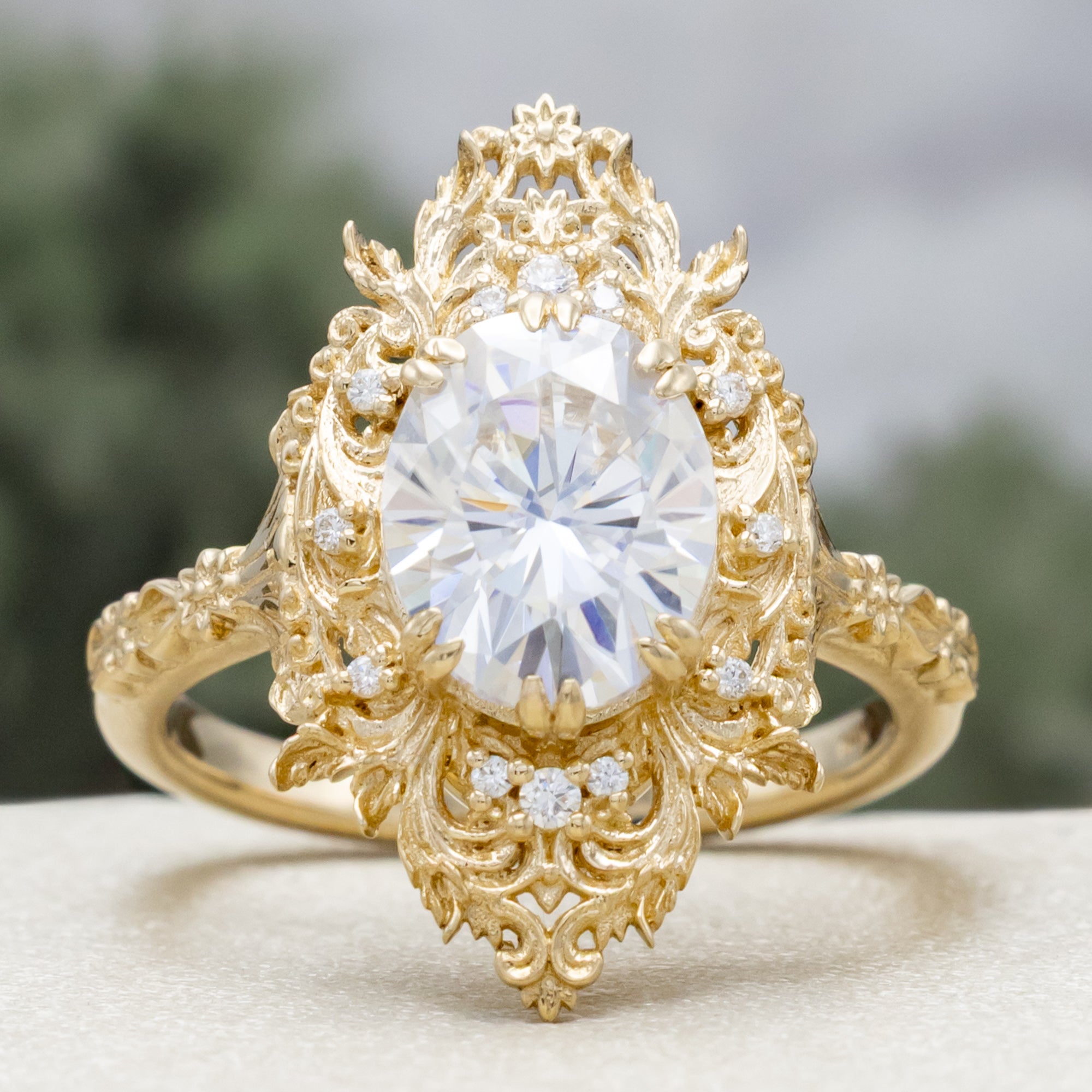 Gold ring with a large moissanite and intricate filigree on a neutral background