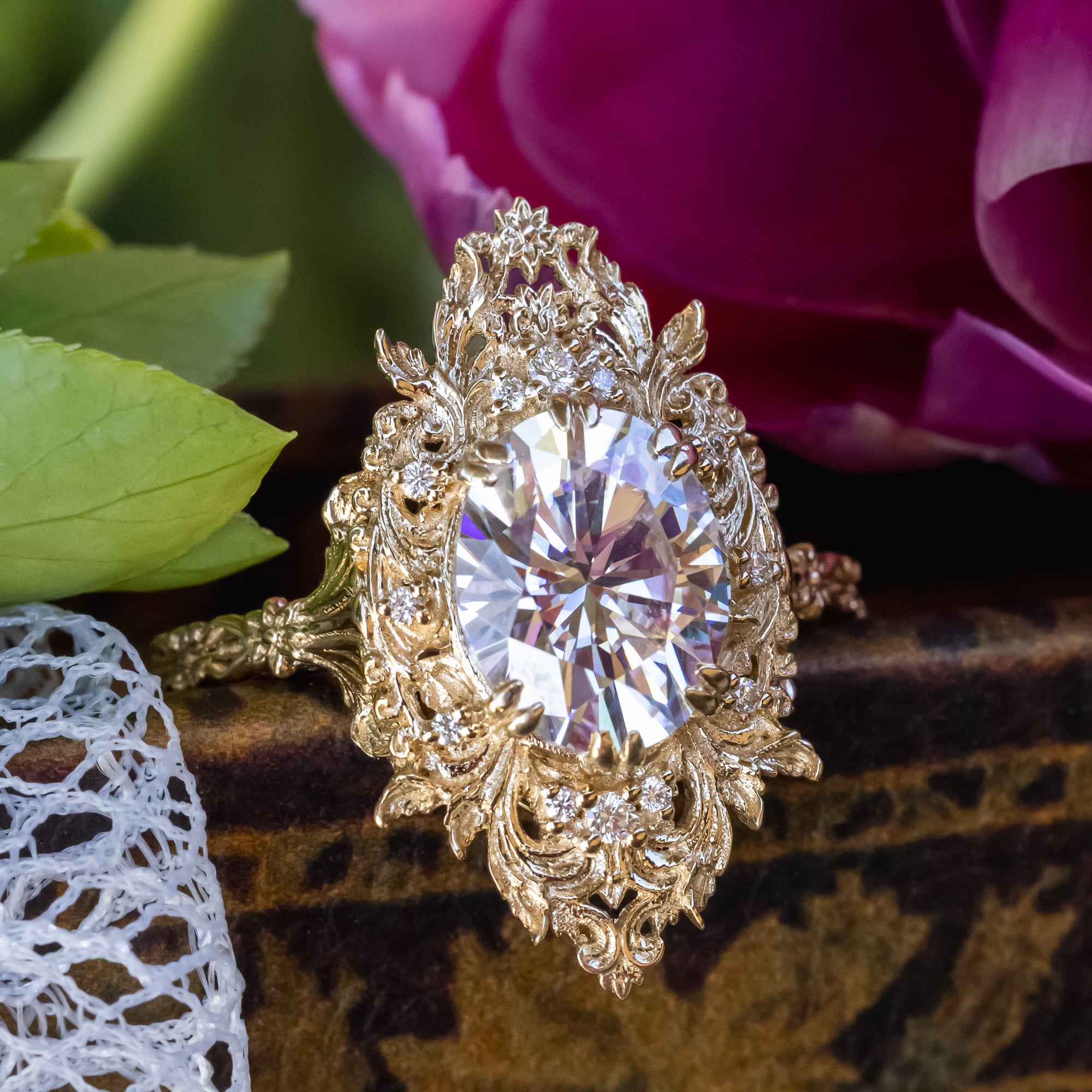 Gold ring with a large moissanite and diamond accents on a floral background