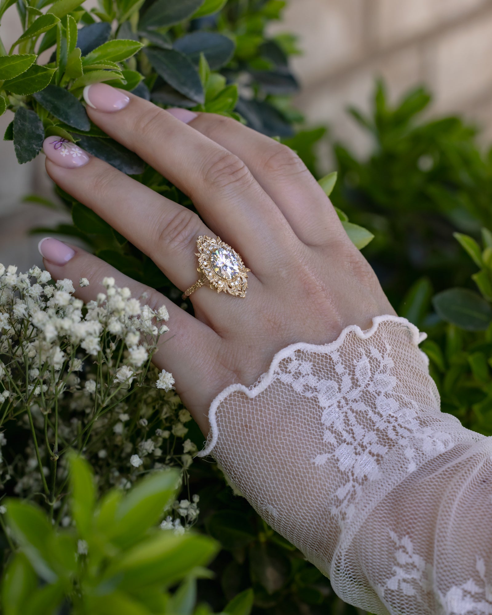 Hand wearing a gold moissanite ring with a floral background