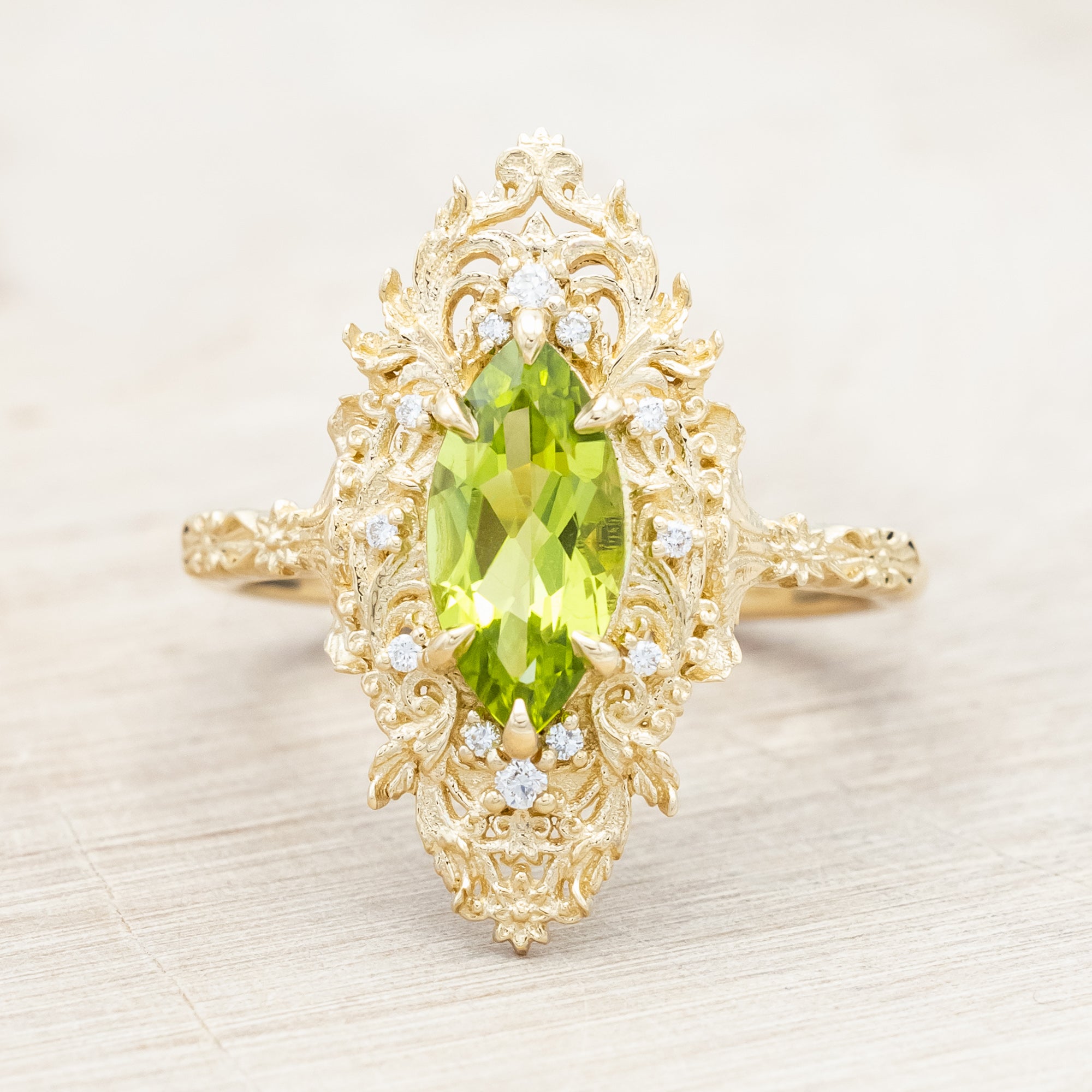 Yellow gold ring with a green peridot on a beige background