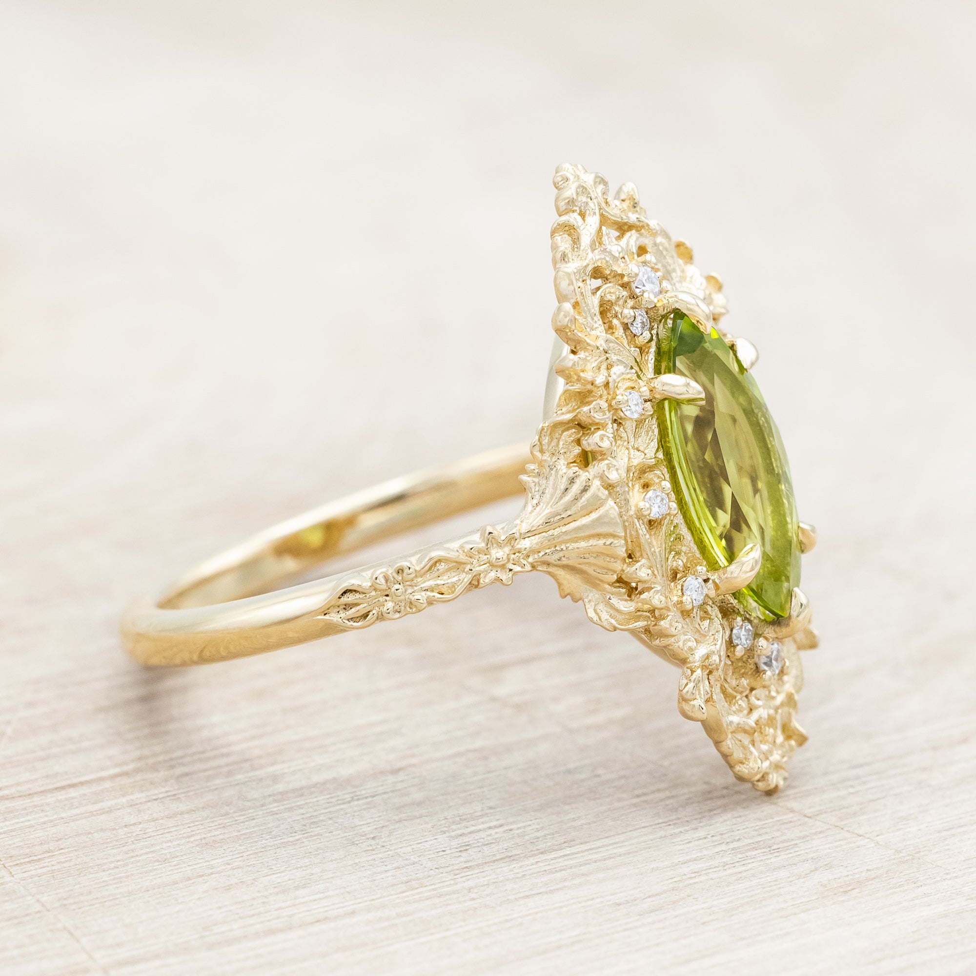 Yellow gold ring with a green peridot on a beige background