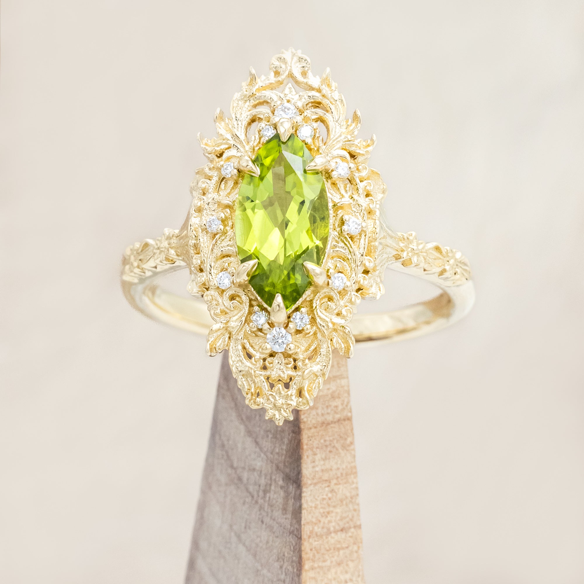 Yellow gold ring with a green peridot on a beige background