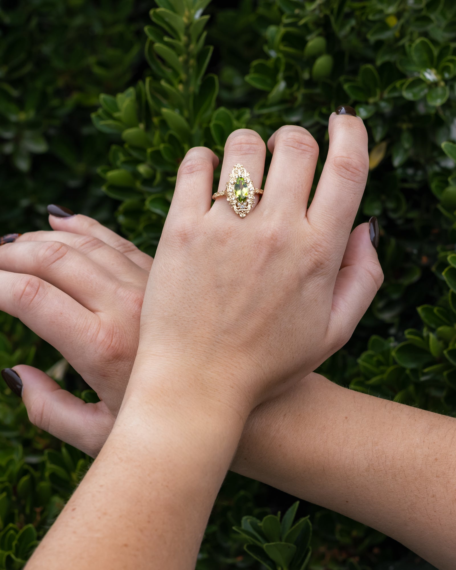 Close-up of hands with a ring on a green leafy background