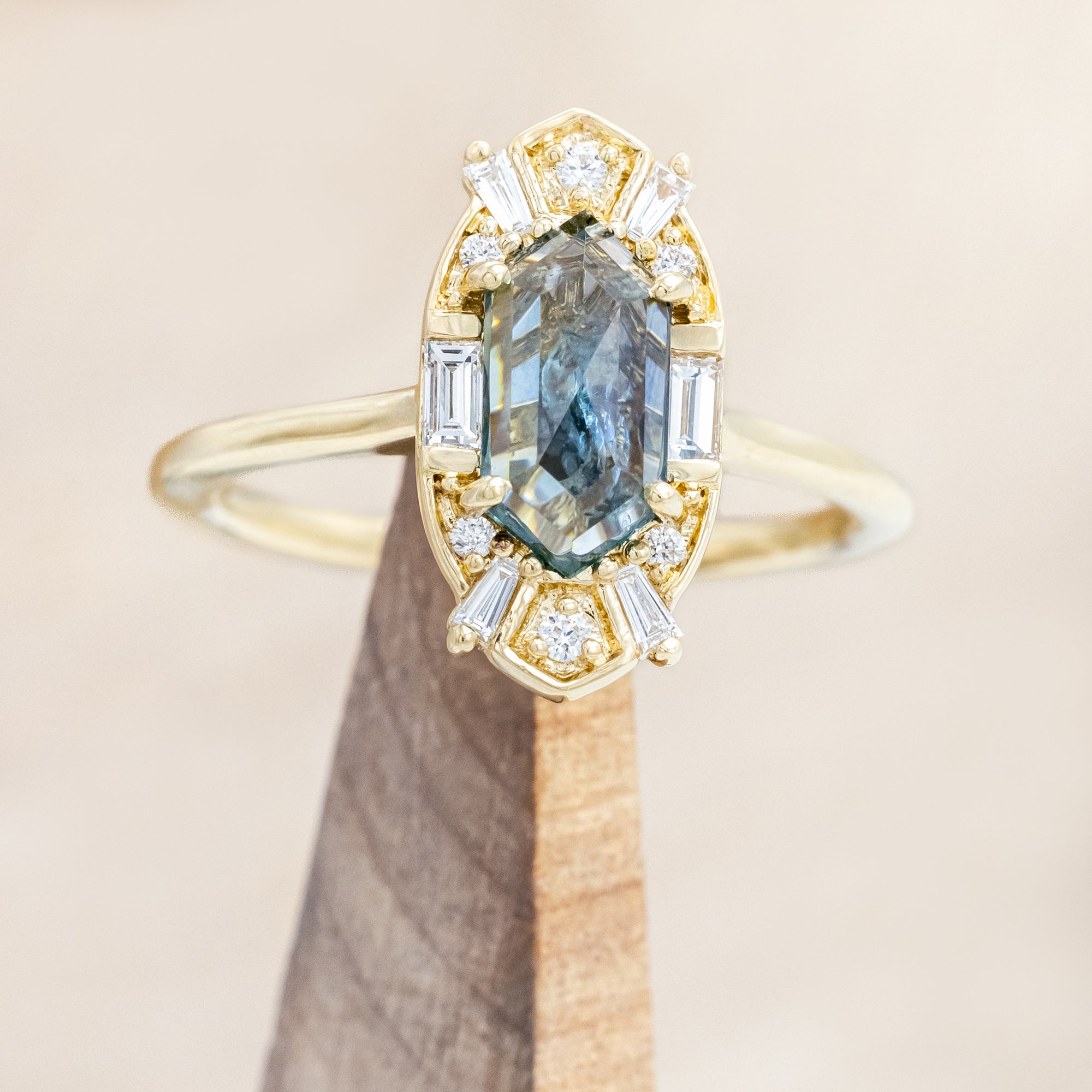 14K gold ring with Montana sapphire and diamond accents on a beige background