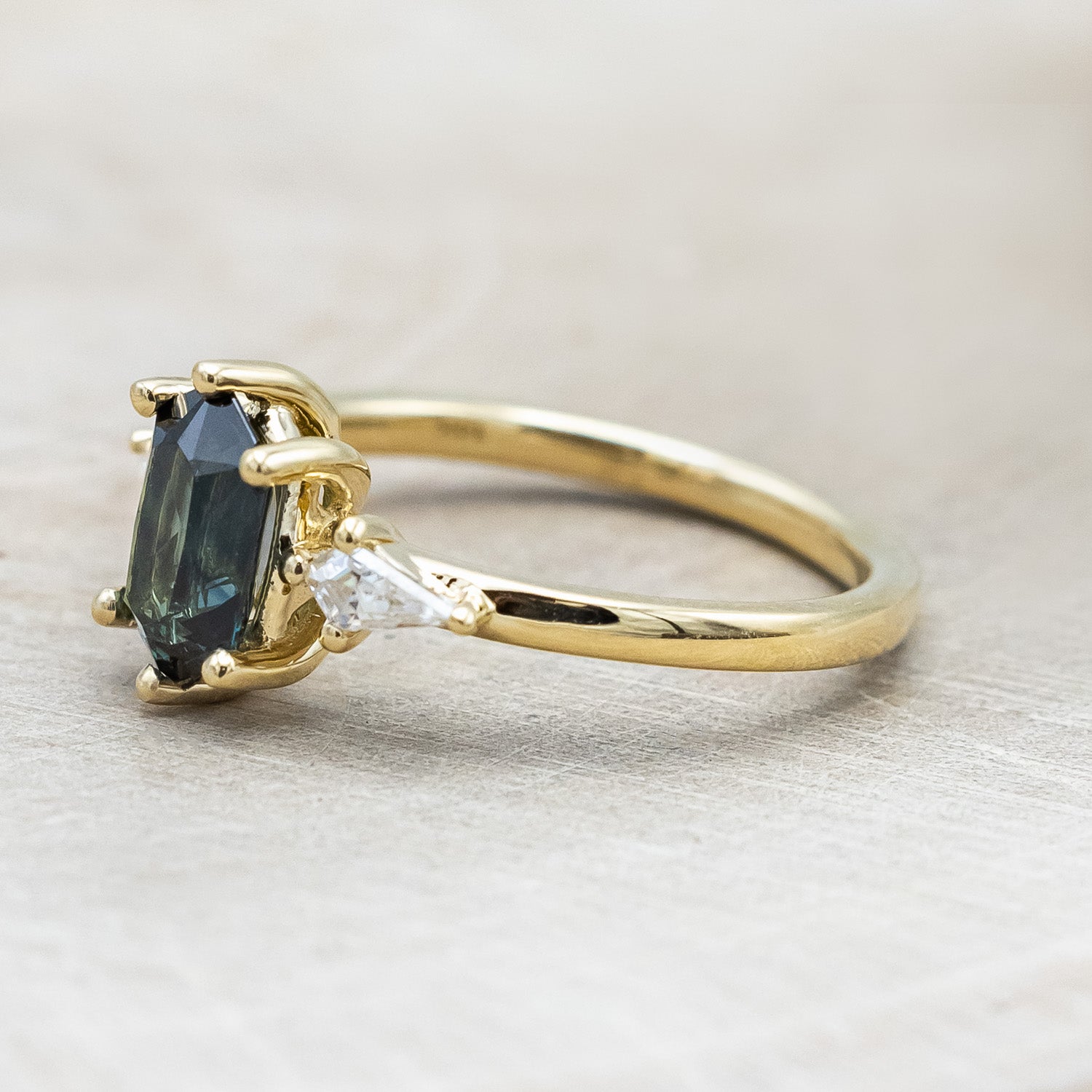 Side view of "Isla" - elongated hexagon cut Australian sapphire with moissanite accents in 14K yellow gold
