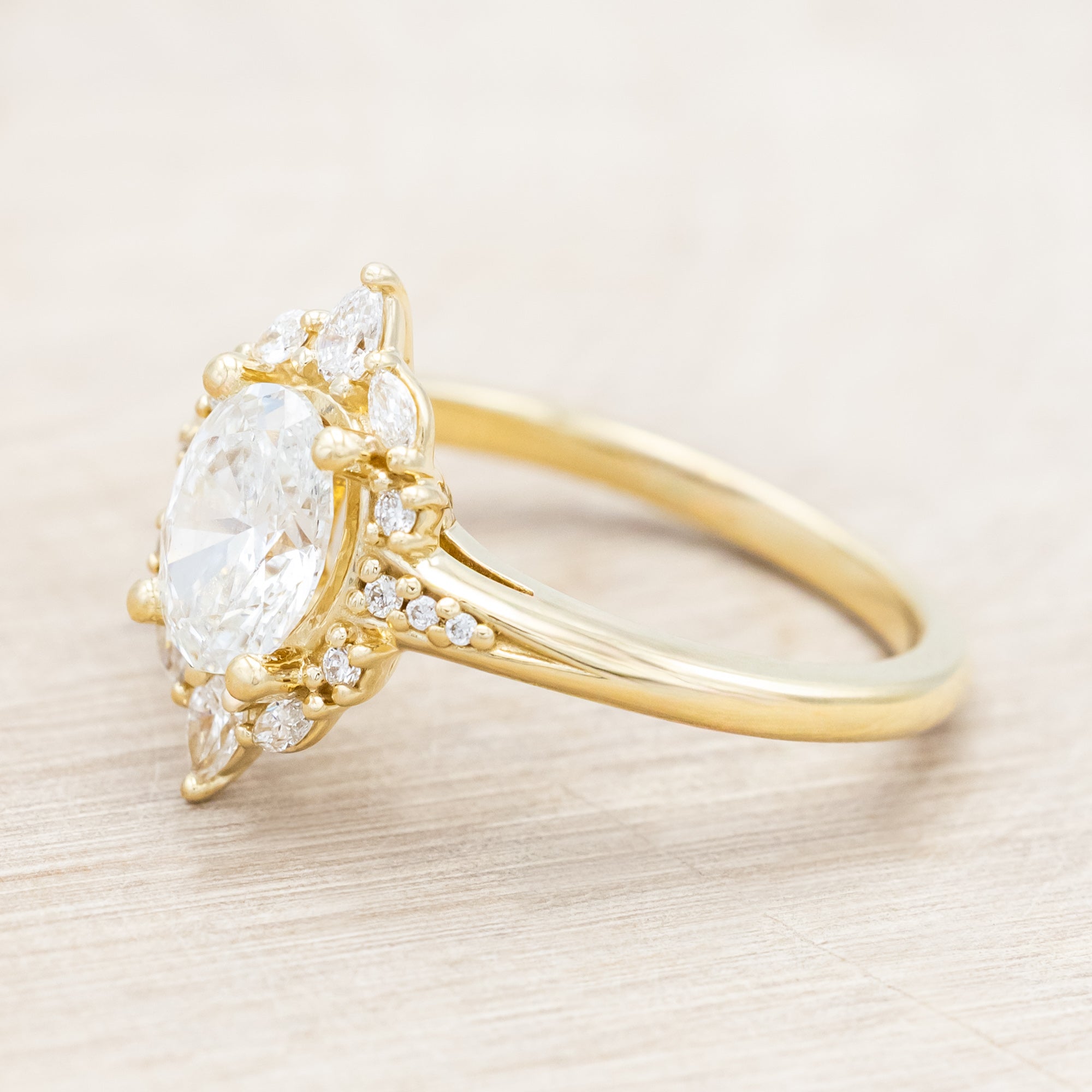 14K gold ring with an oval lab diamond on a beige background