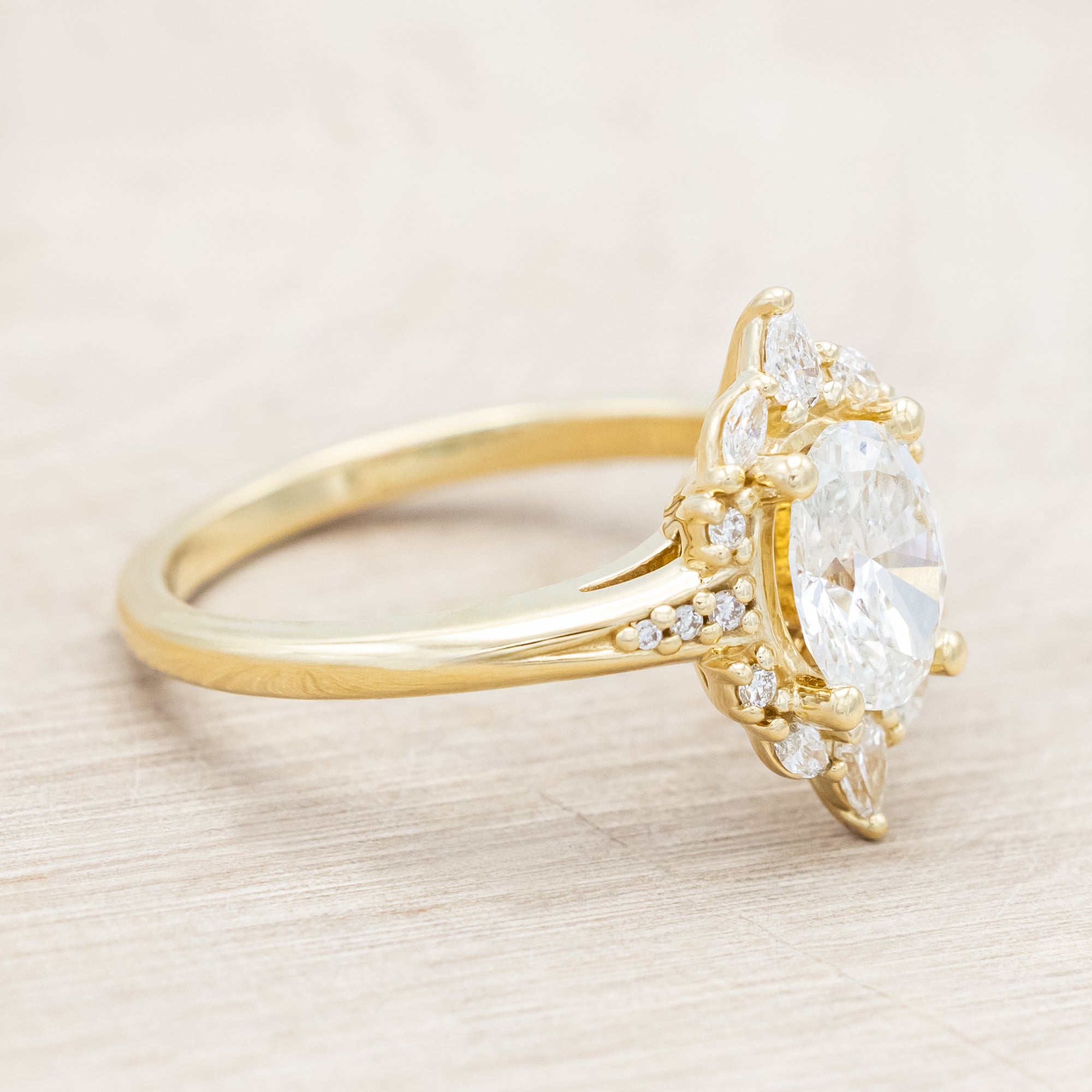 14K gold ring with an oval lab diamond on a beige background