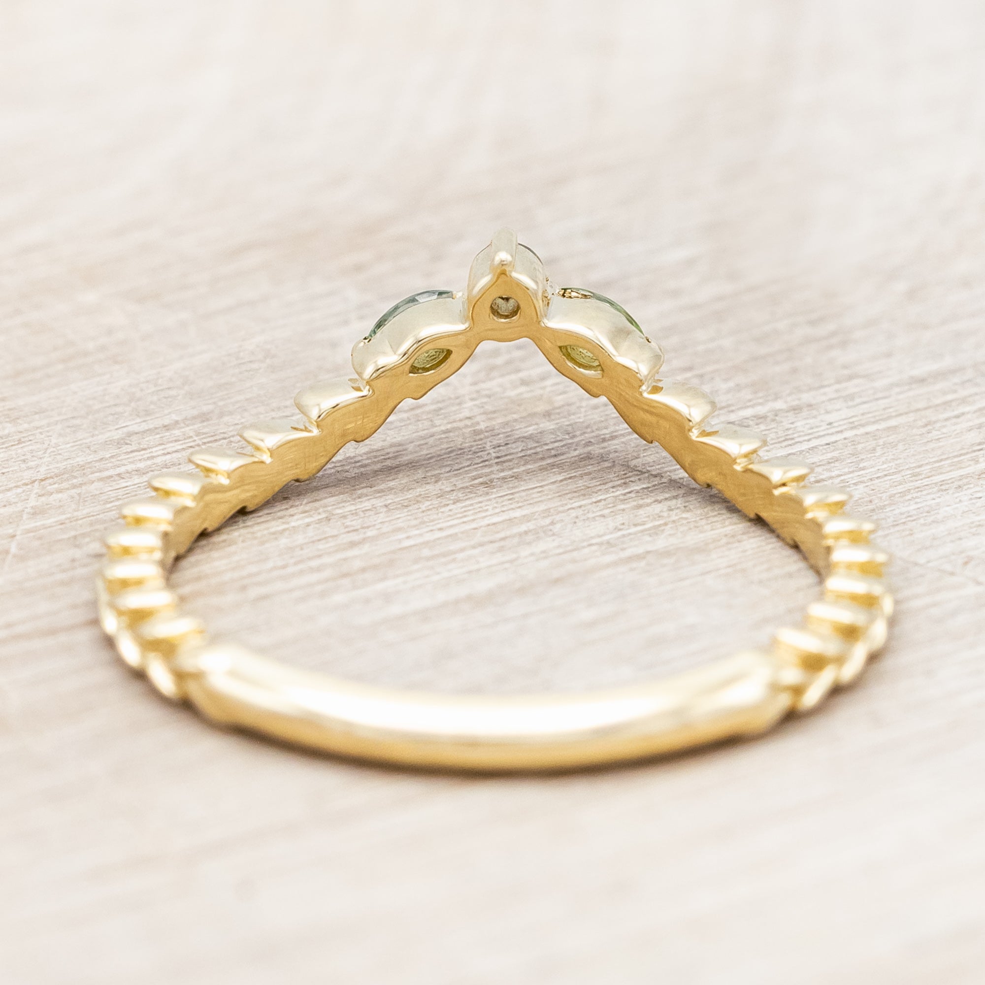 Gold ring with sapphire and tourmaline accents against a beige background