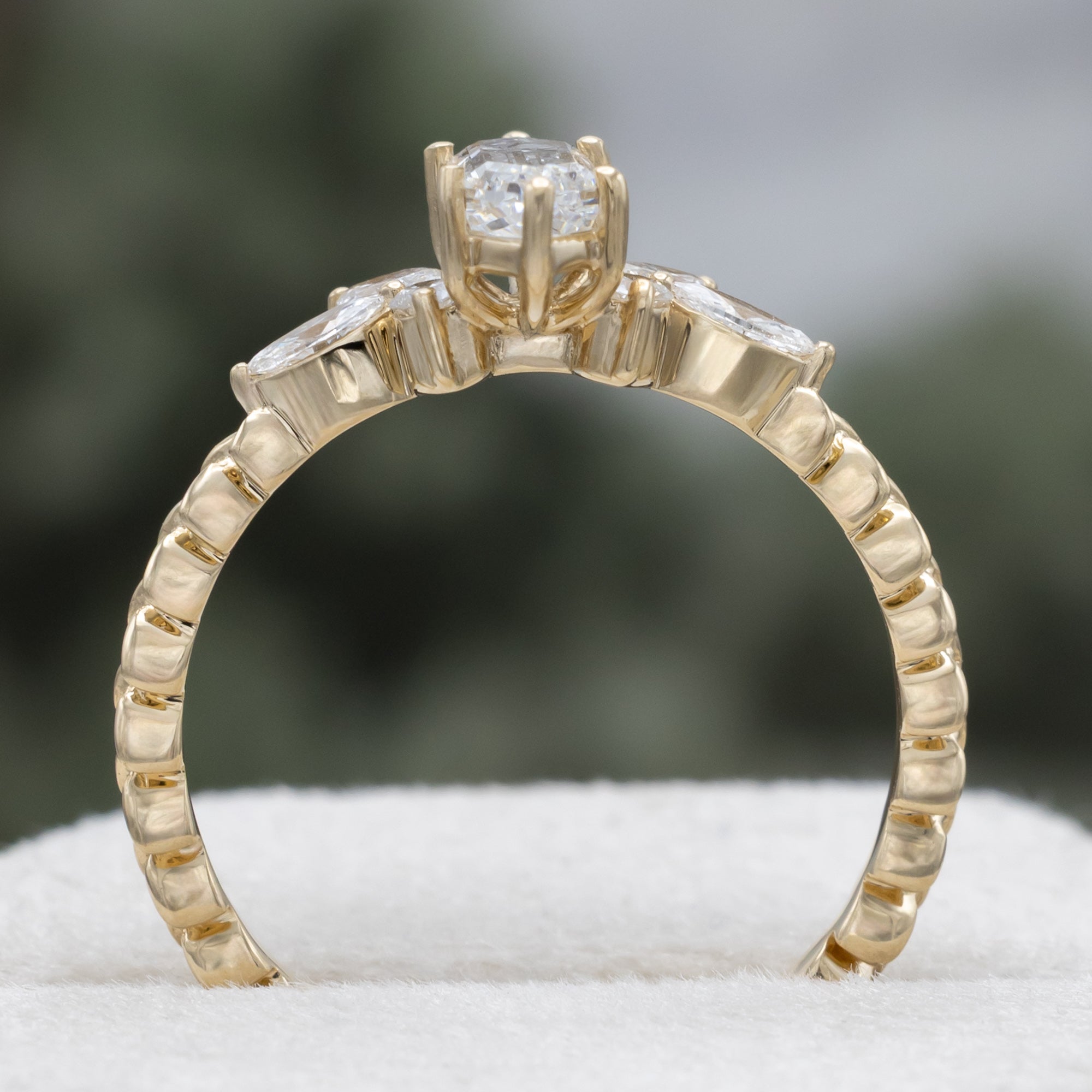 Gold ring with diamond centerstone and accents on a neutral background