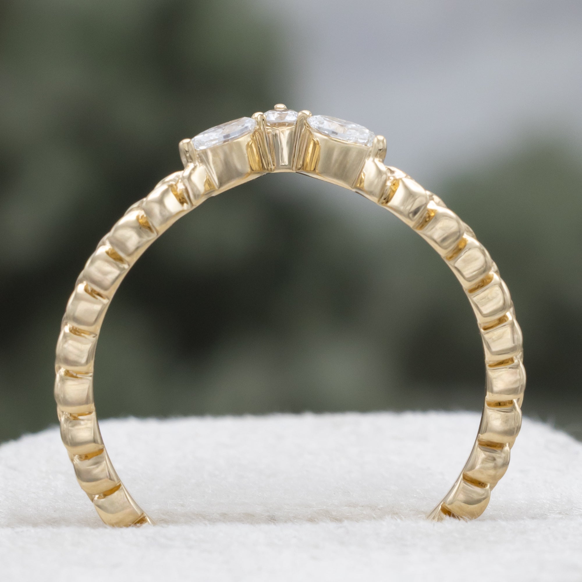 Gold ring with diamond accents on a neutral background