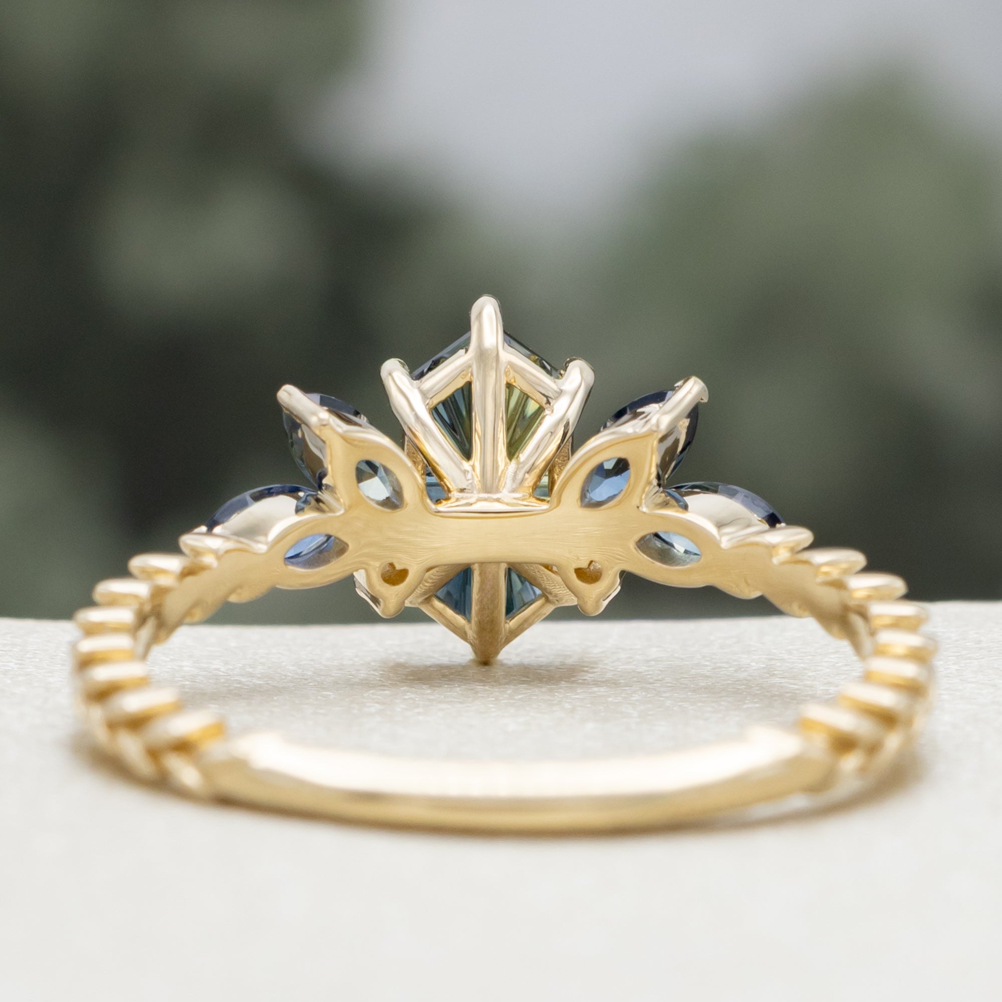 Gold ring with Australian sapphire center stone and diamond accents on a blurred background
