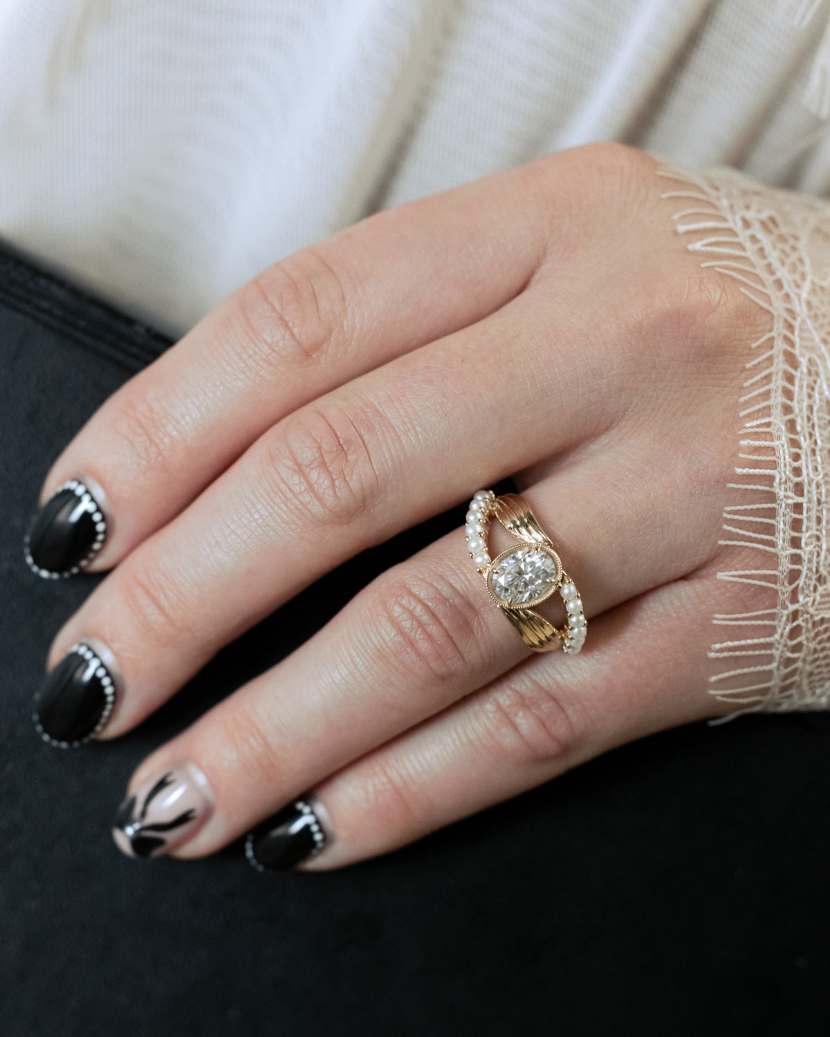 On hand photo of "Lily" an oval cut moissanite women's engagement ring with pearl accents