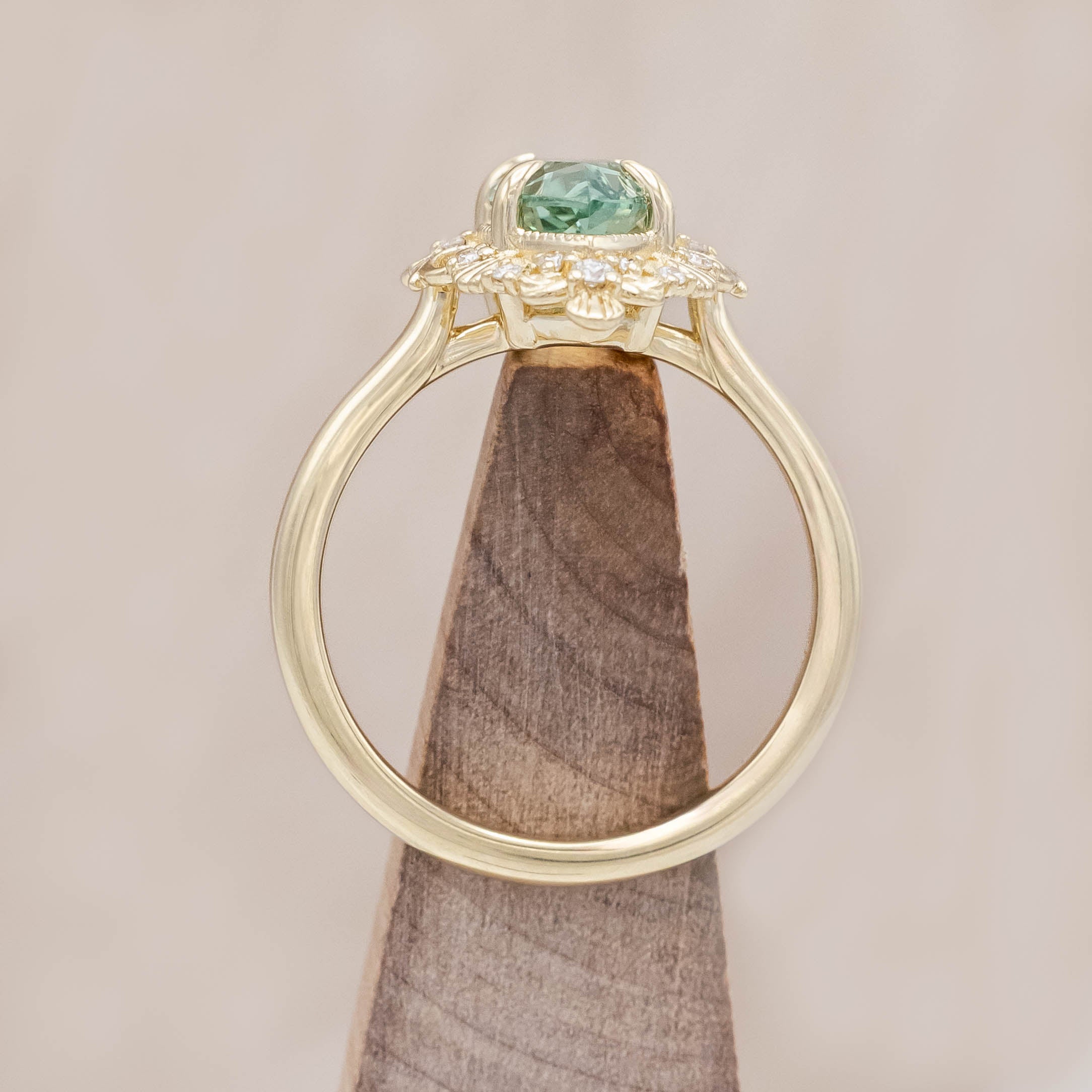 14K gold ring with a green sapphire on a light wooden background