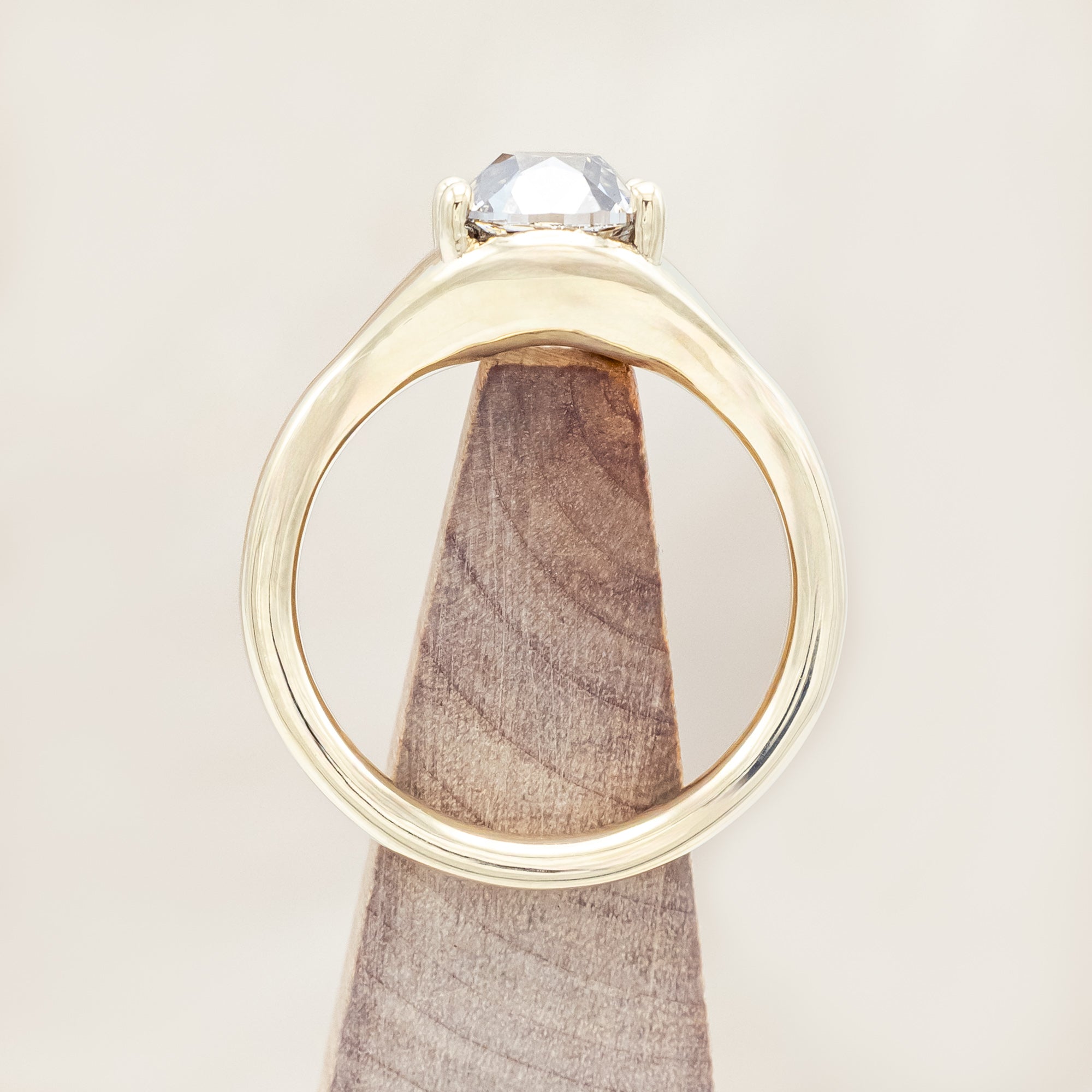 Gold ring with a large salt & pepper diamond against a beige background