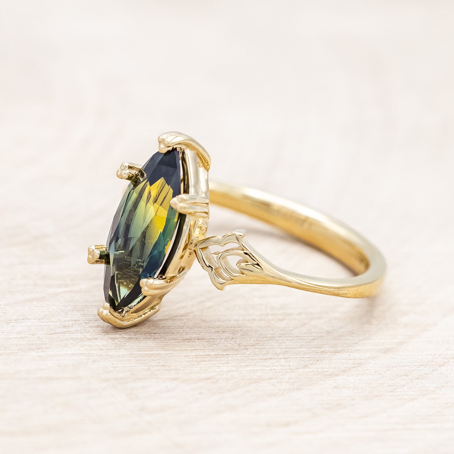 Side view of "Morrigan" - solitaire Australian sapphire women's engagement ring on an ornate 14K yellow gold band