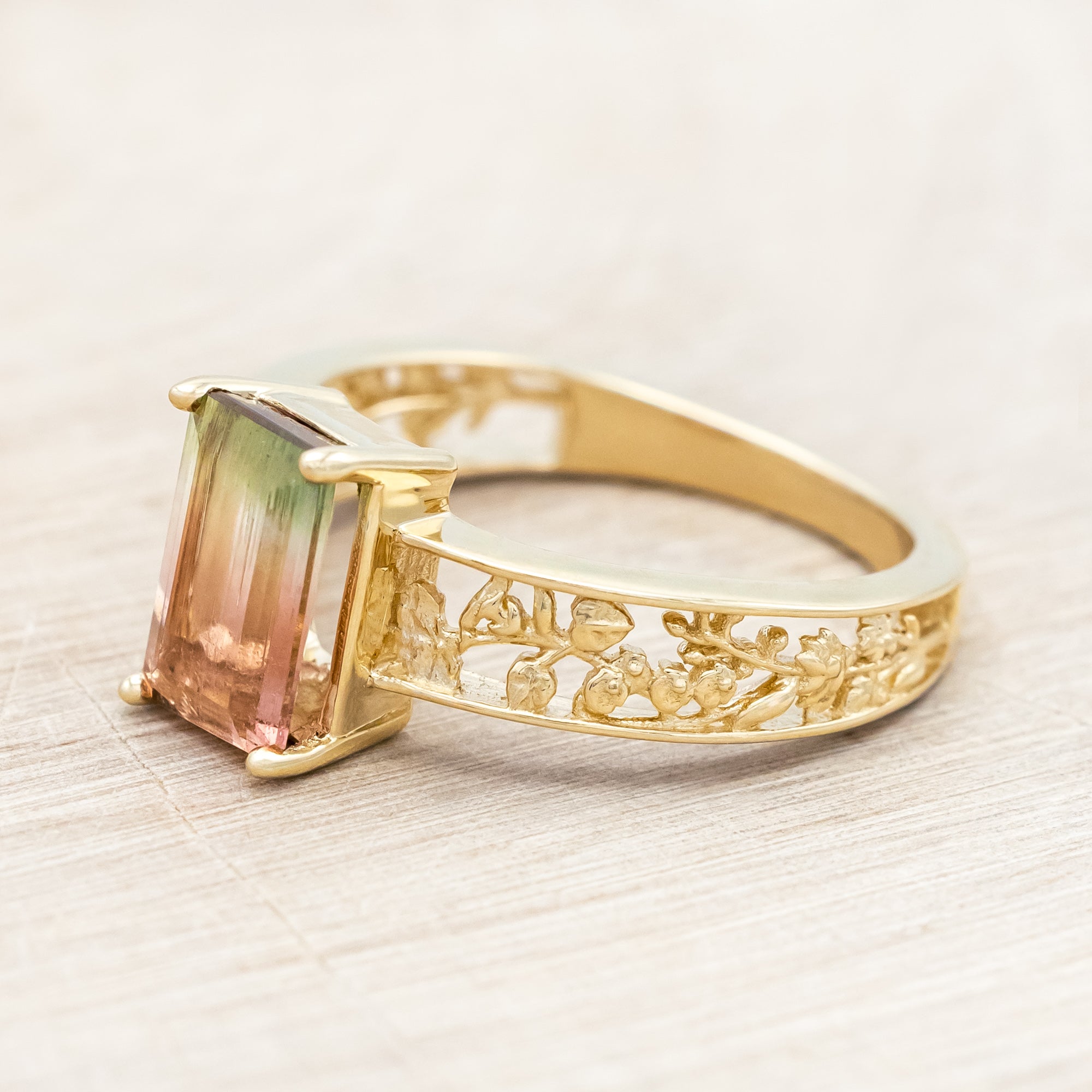 14K gold ring with a green and pink gemstone on a beige background