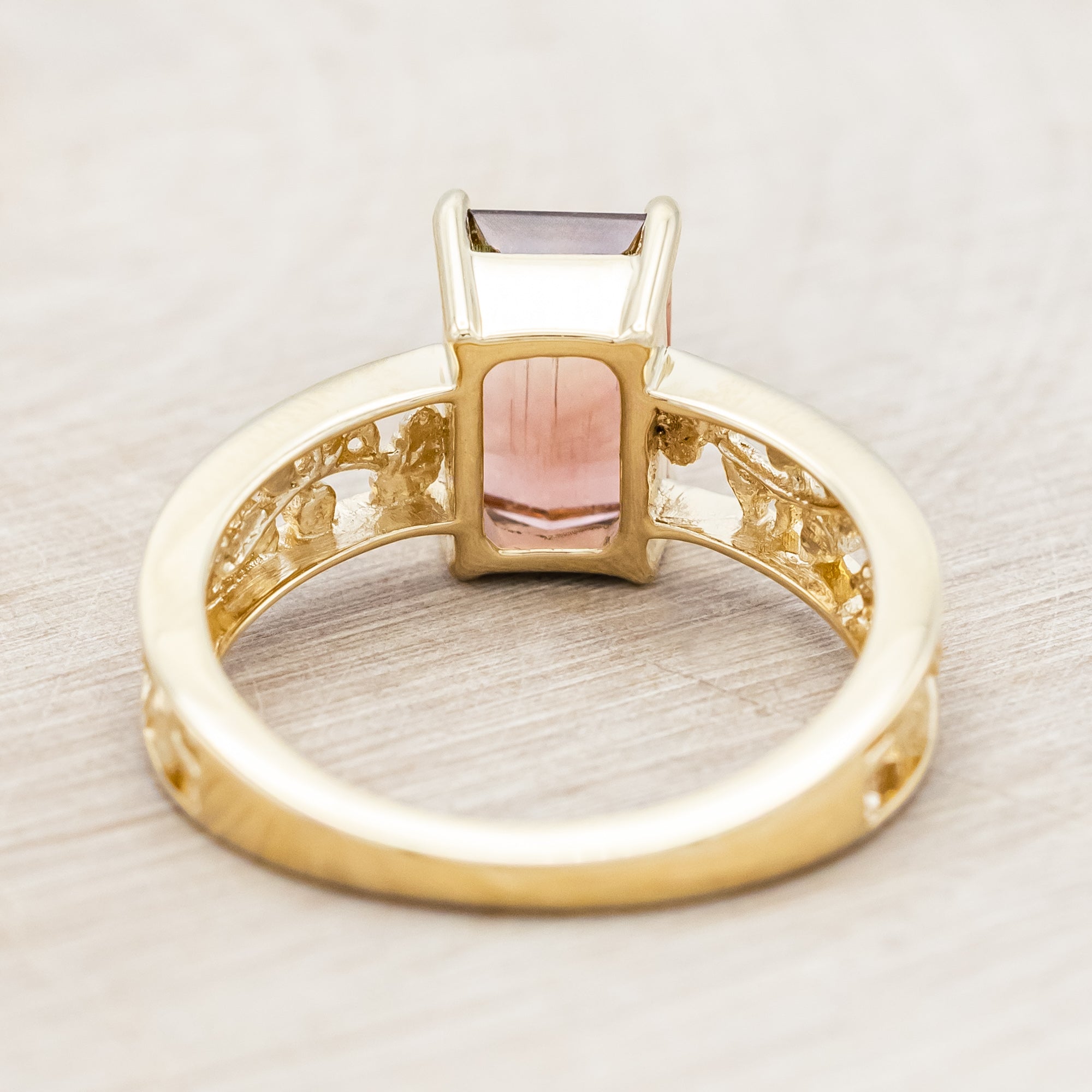 14K gold ring with a green and pink gemstone on a beige background