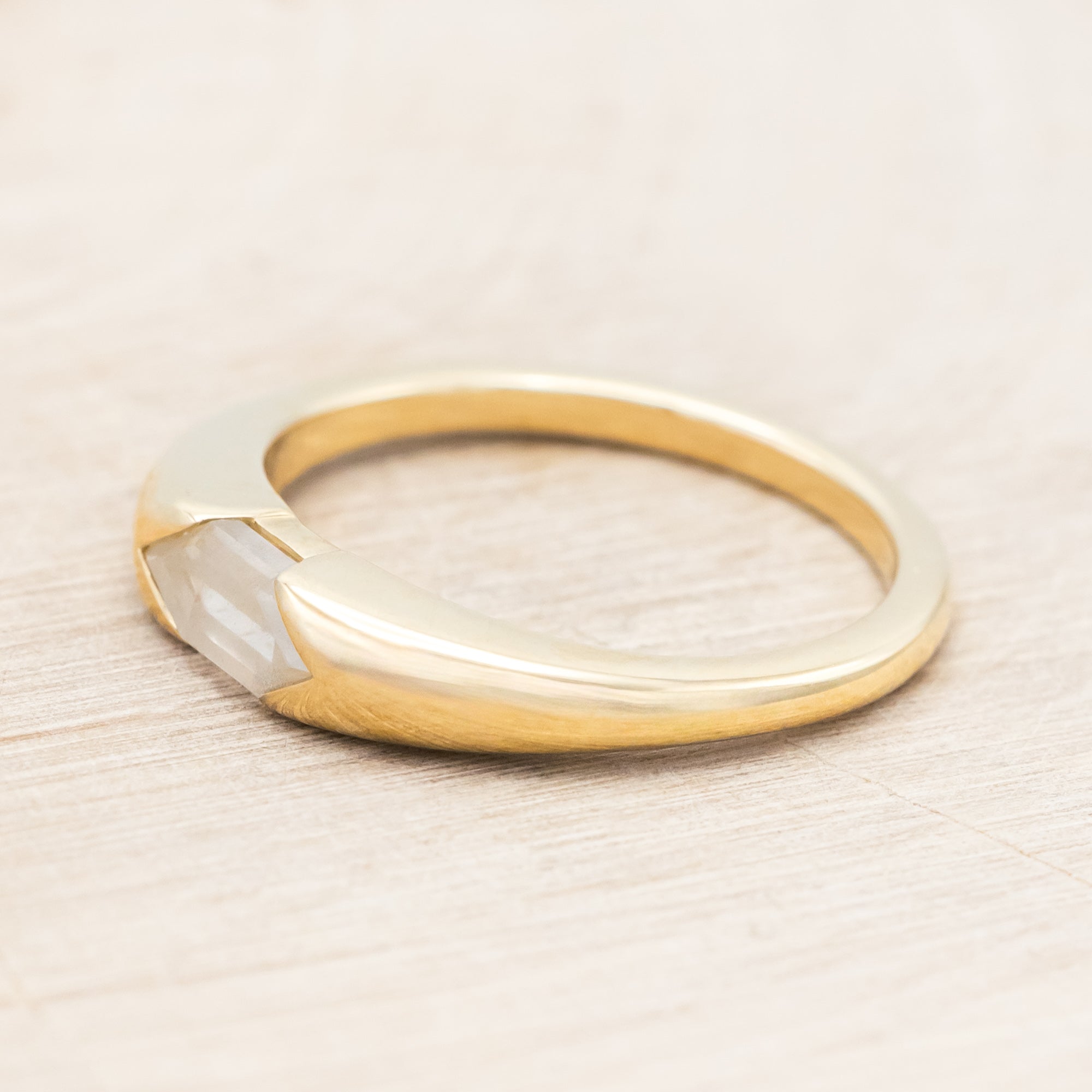 14K gold ring with a geometric stone on a wooden background