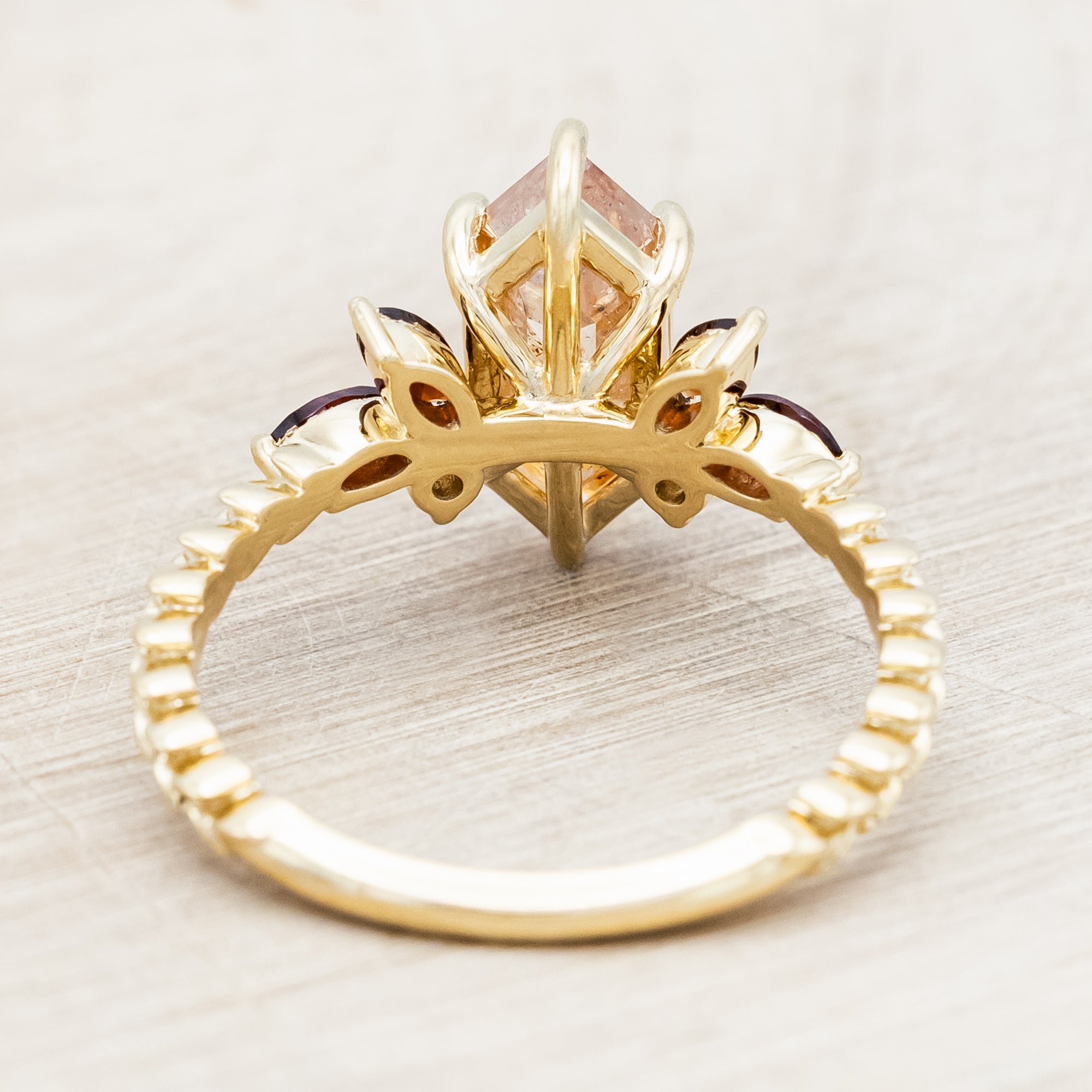 Gold ring featuring salt & pepper diamond with garnet and champagne diamond accents on a neutral background