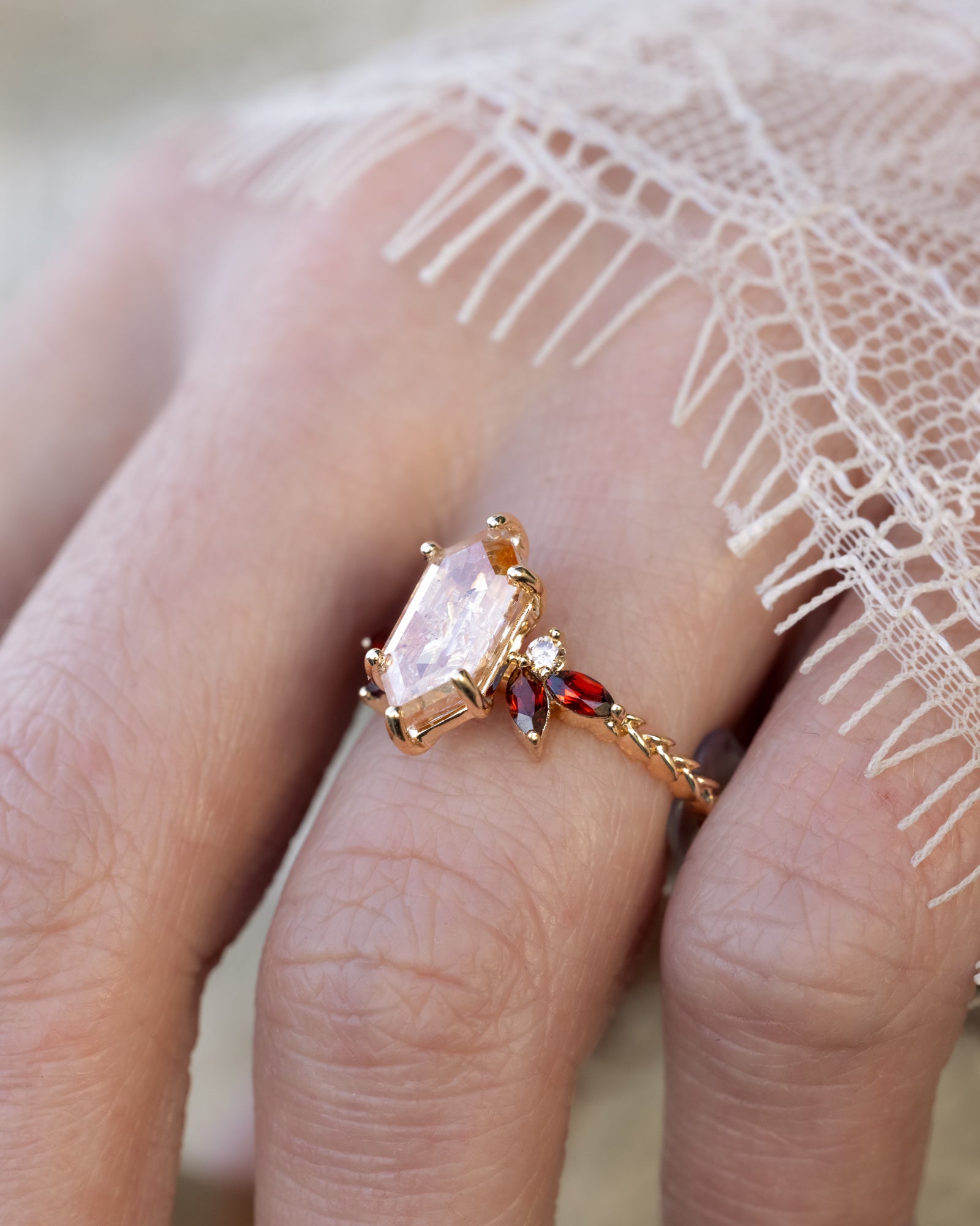 Hand with lace sleeve wearing gold ring with salt & pepper diamond