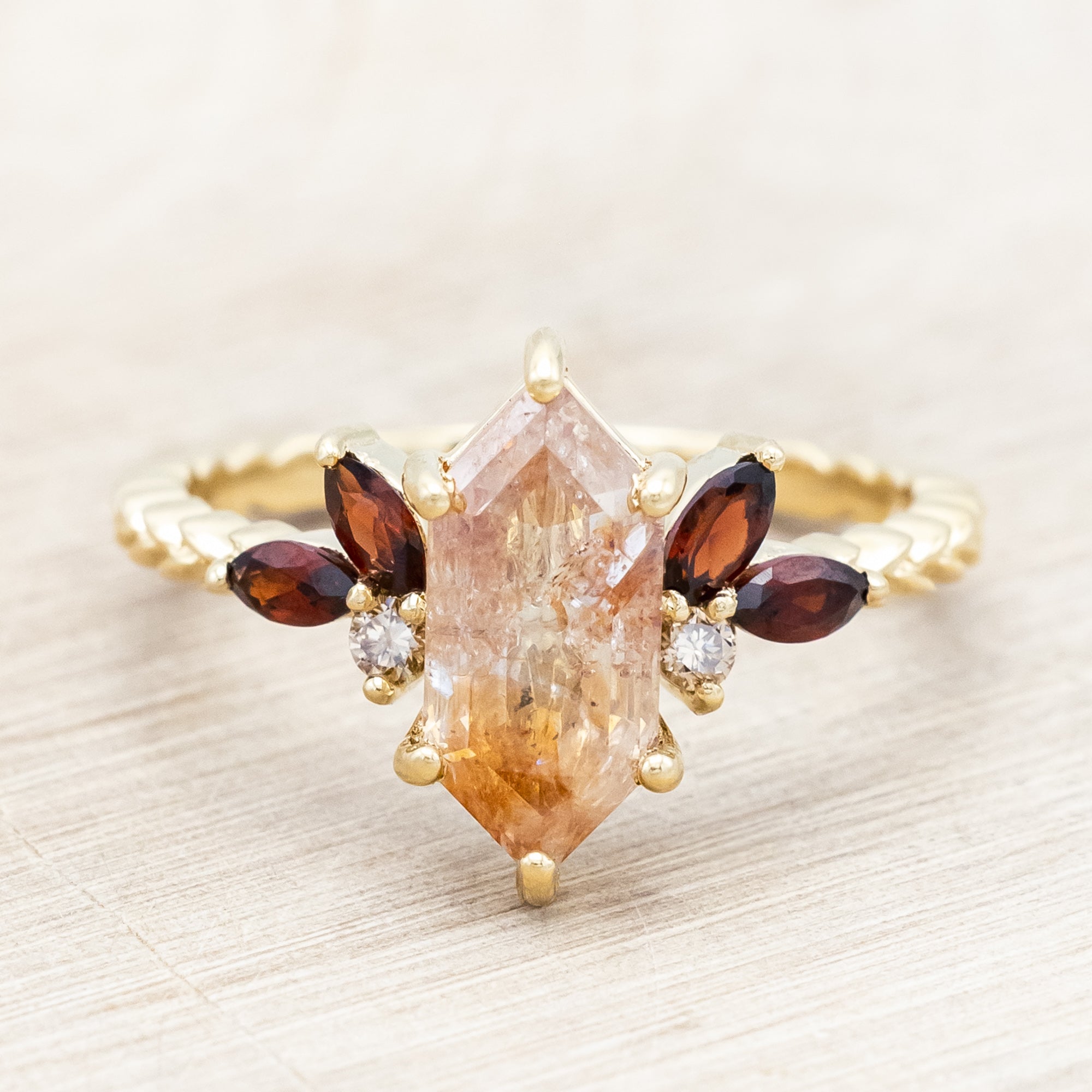 Gold ring featuring salt & pepper diamond with garnet and champagne diamond accents on a neutral background