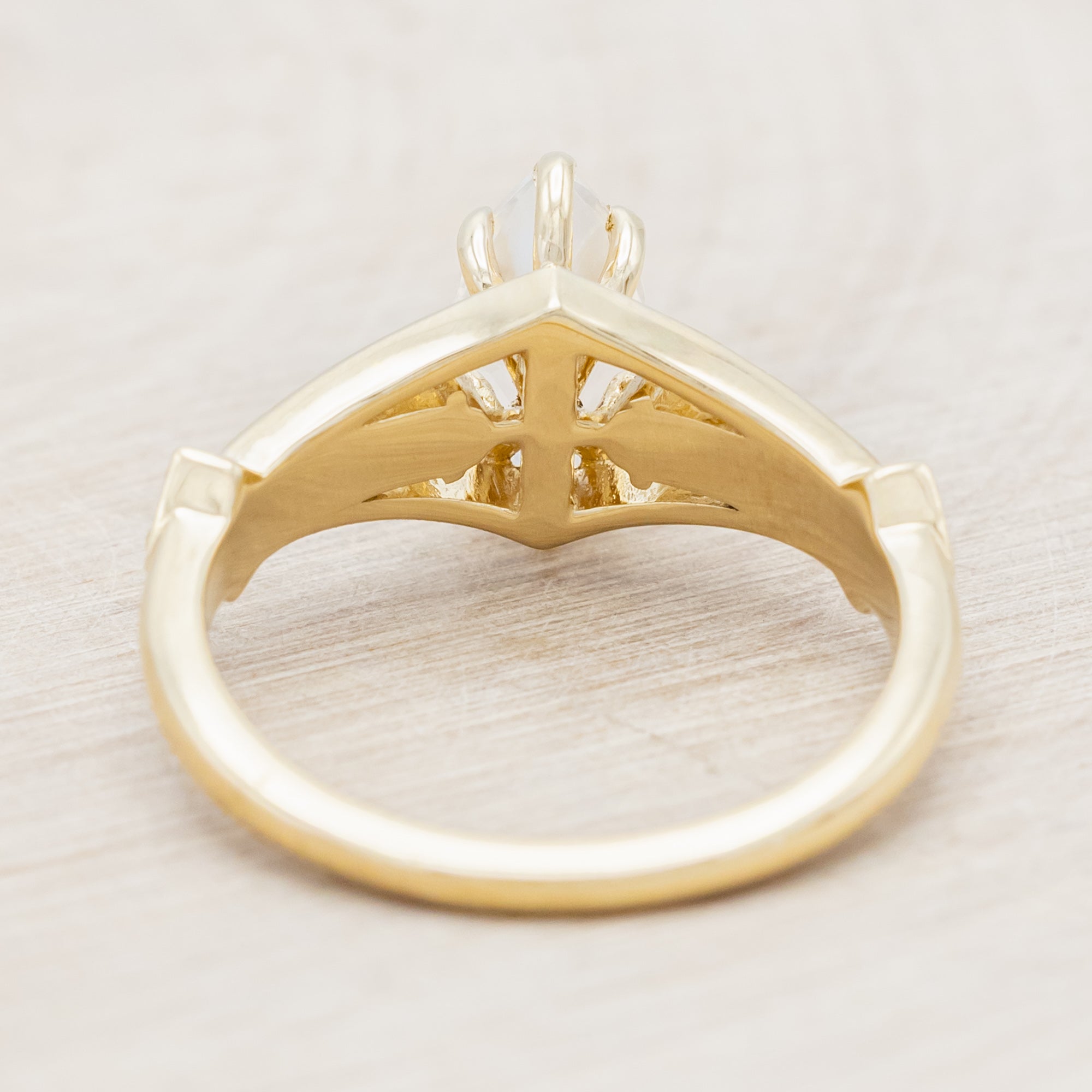 Yellow gold ring with a moonstone and smaller diamonds on a beige background