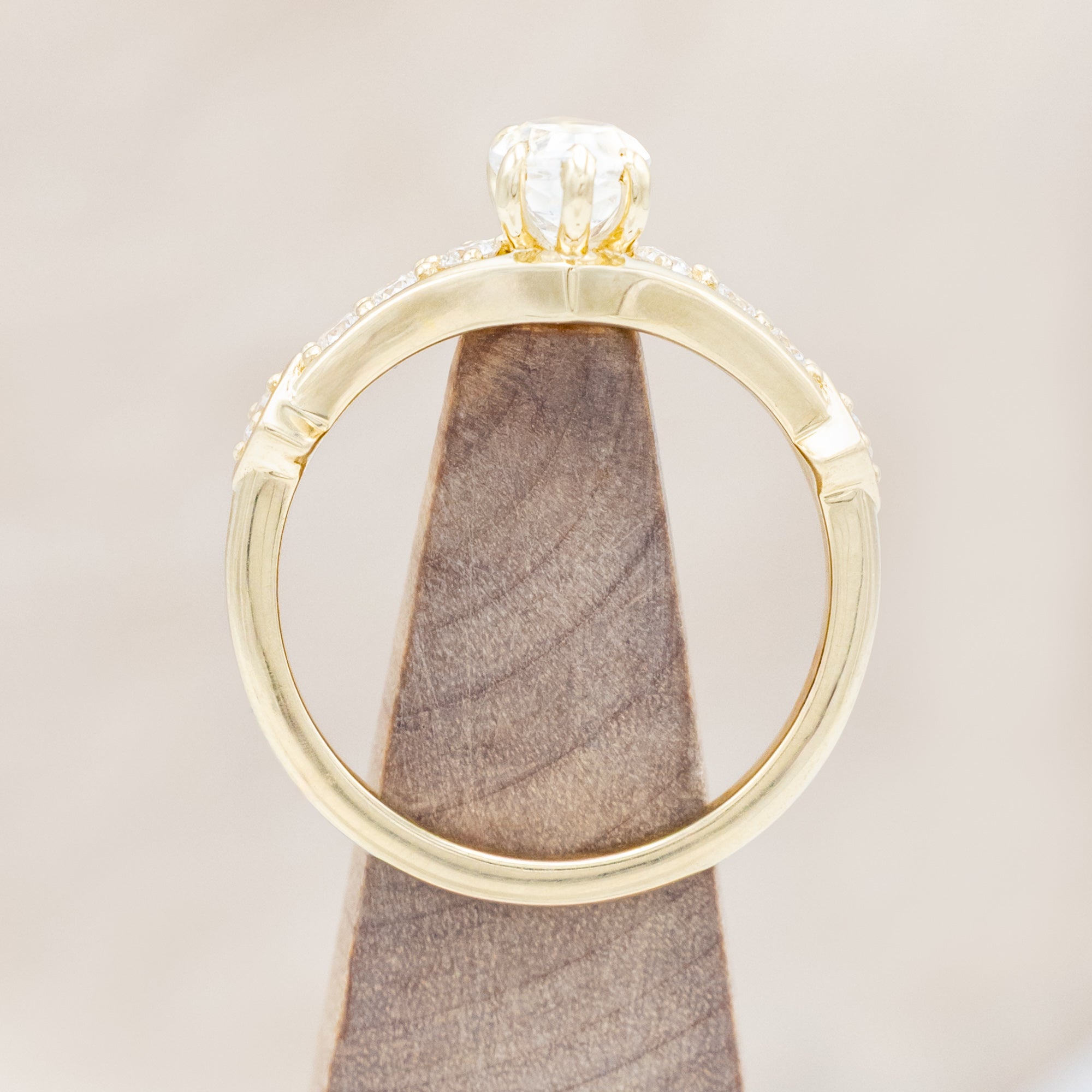 Yellow gold ring with a moonstone and smaller diamonds on a beige background