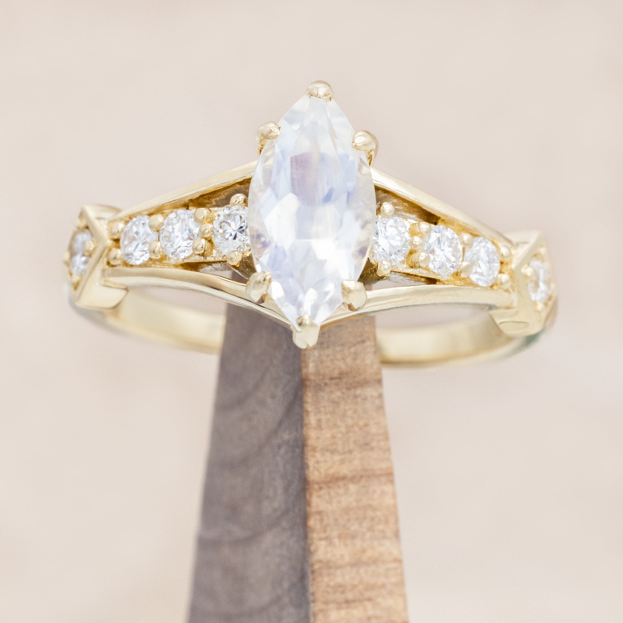 Yellow gold ring with a moonstone and smaller diamonds on a beige background