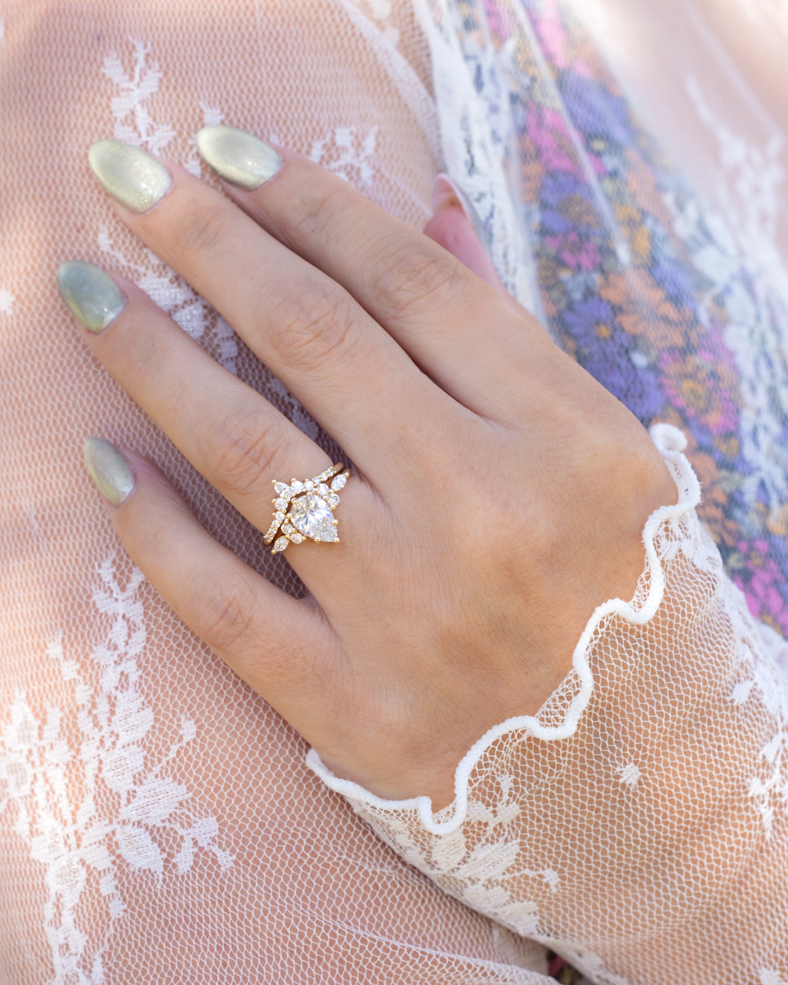 Hand wearing a lab diamond ring on a lace fabric background