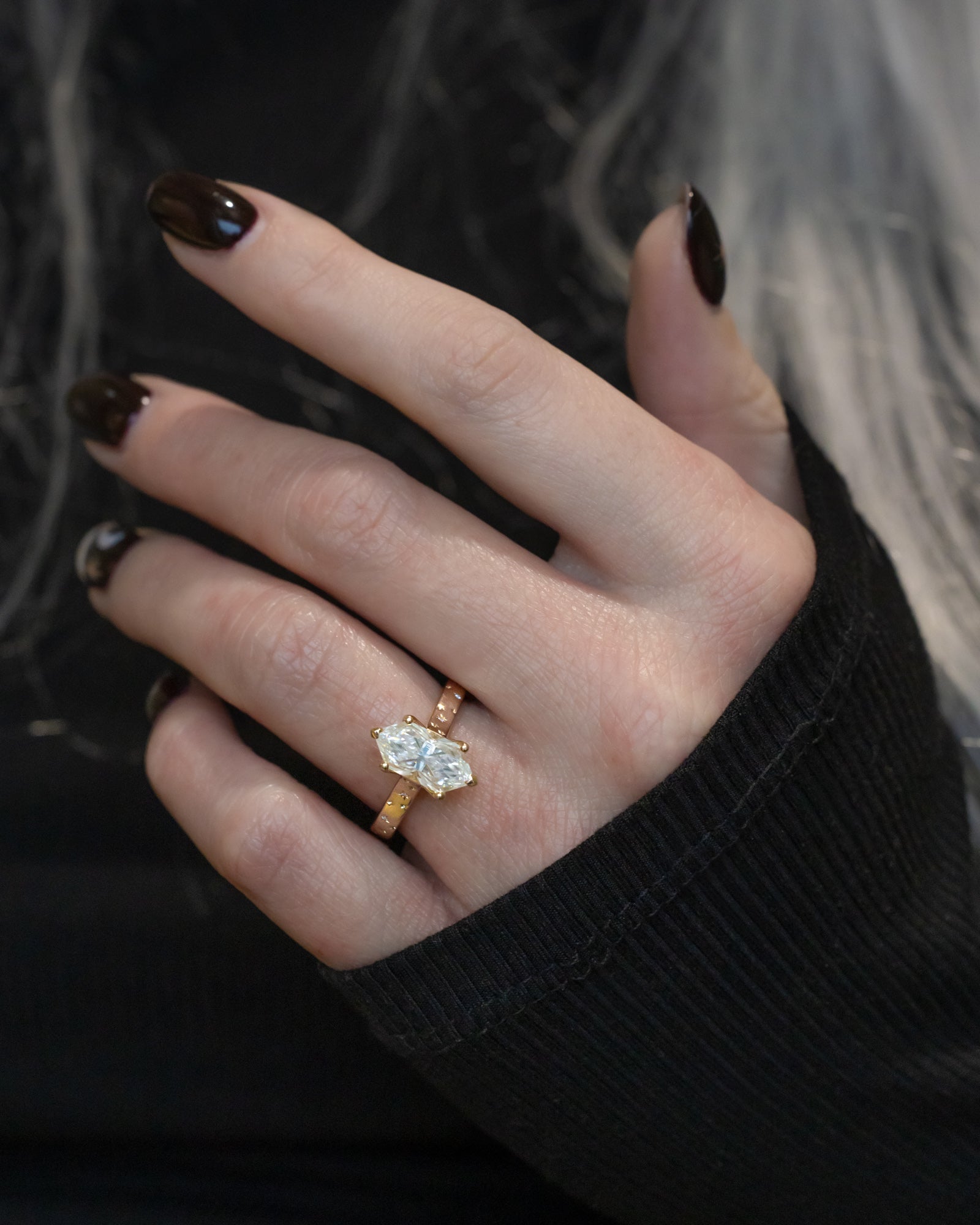 Hand wearing a moissanite ring with a blurred background