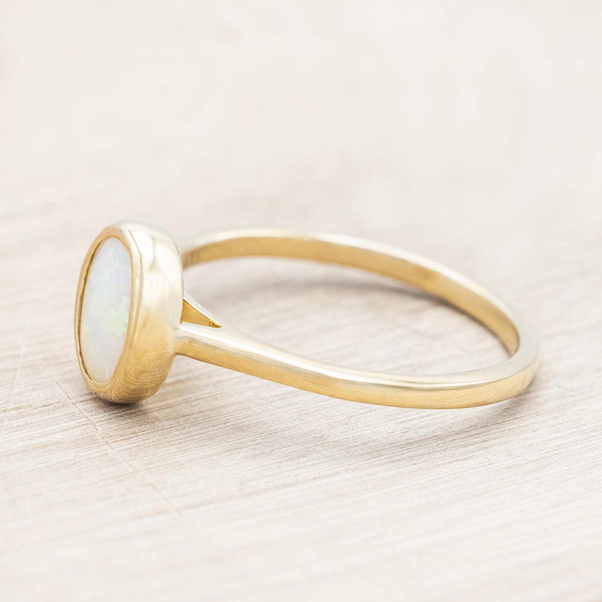 Gold ring with an opal center stone on a neutral background