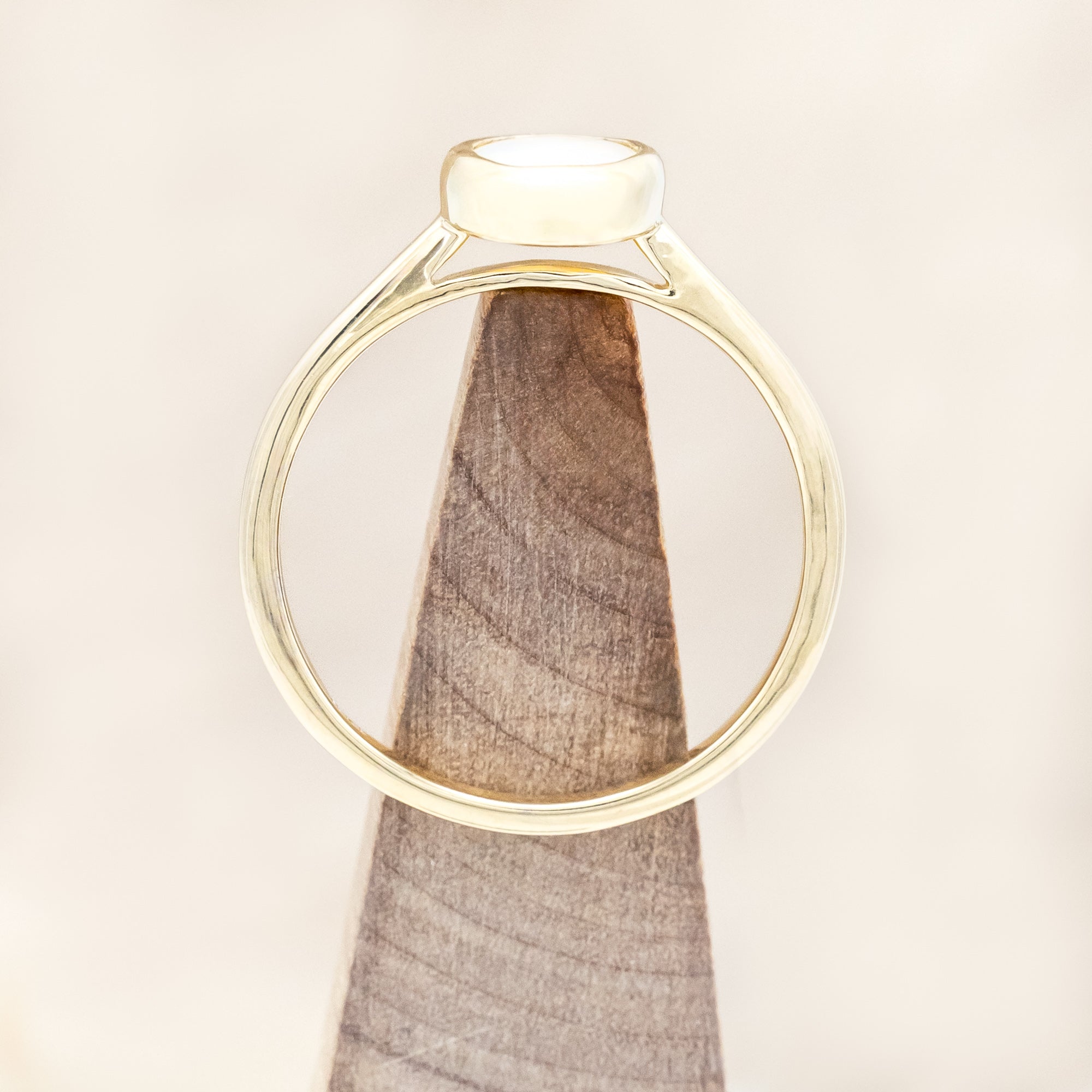 Gold ring with an opal center stone on a neutral background