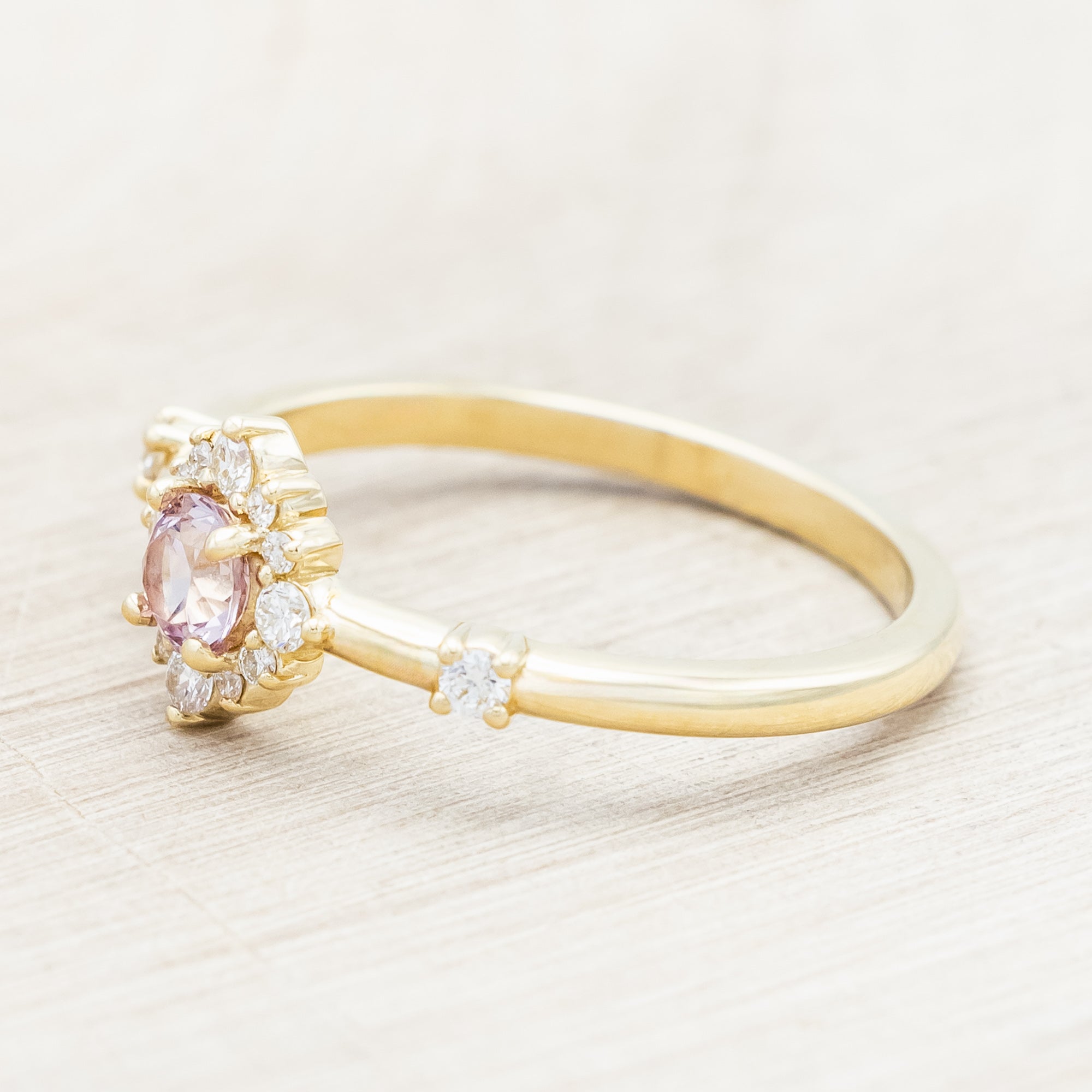 Gold ring with a dragon garnet and diamond accents on a light wooden surface