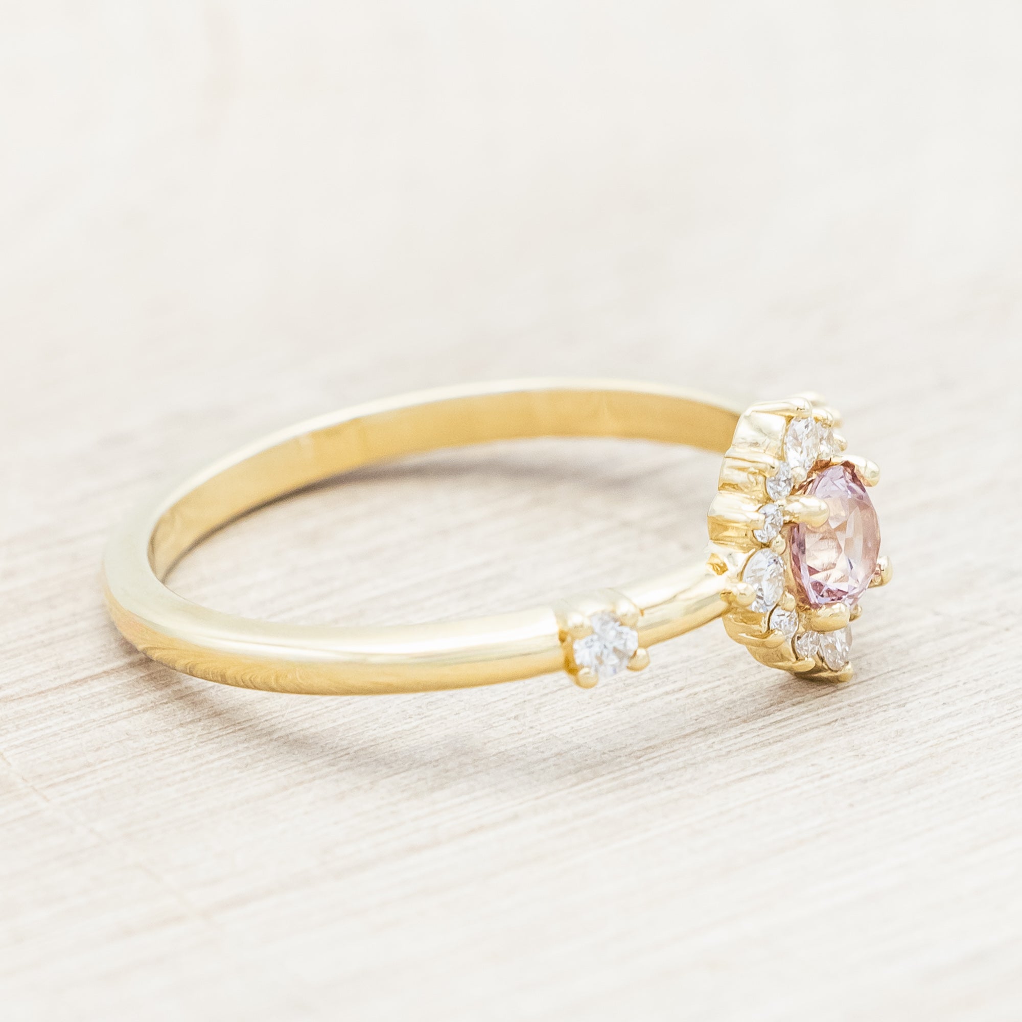 Gold ring with a dragon garnet and diamond accents on a light wooden surface