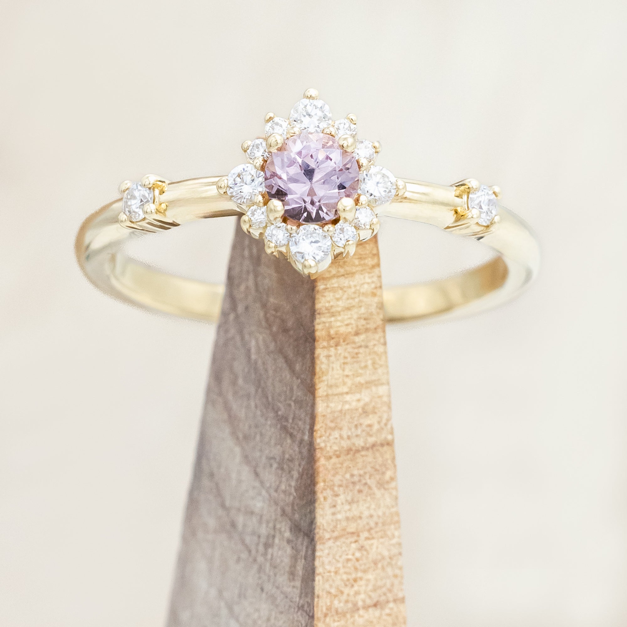 Gold ring with a dragon garnet on a wooden stand against a beige background