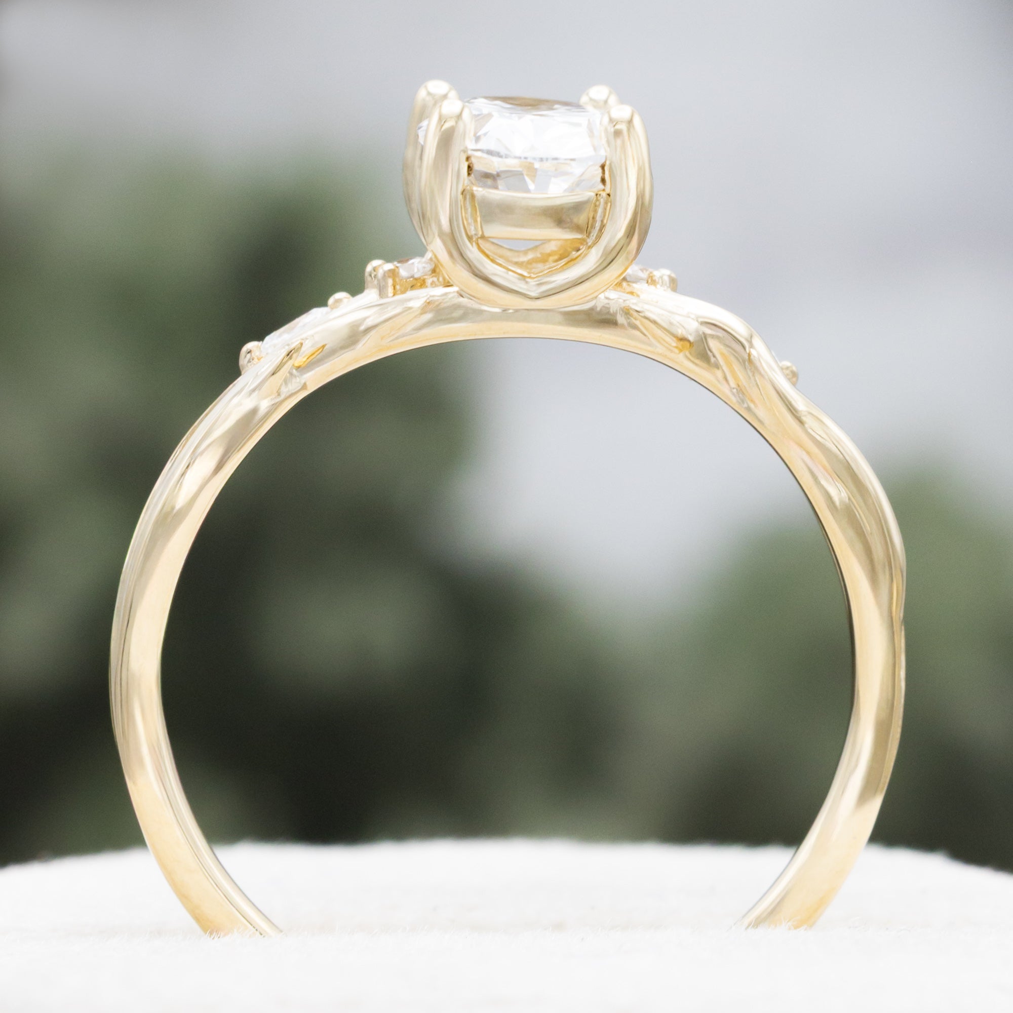 14K gold engagement ring with oval lab-grown diamond and accents against a blurred background