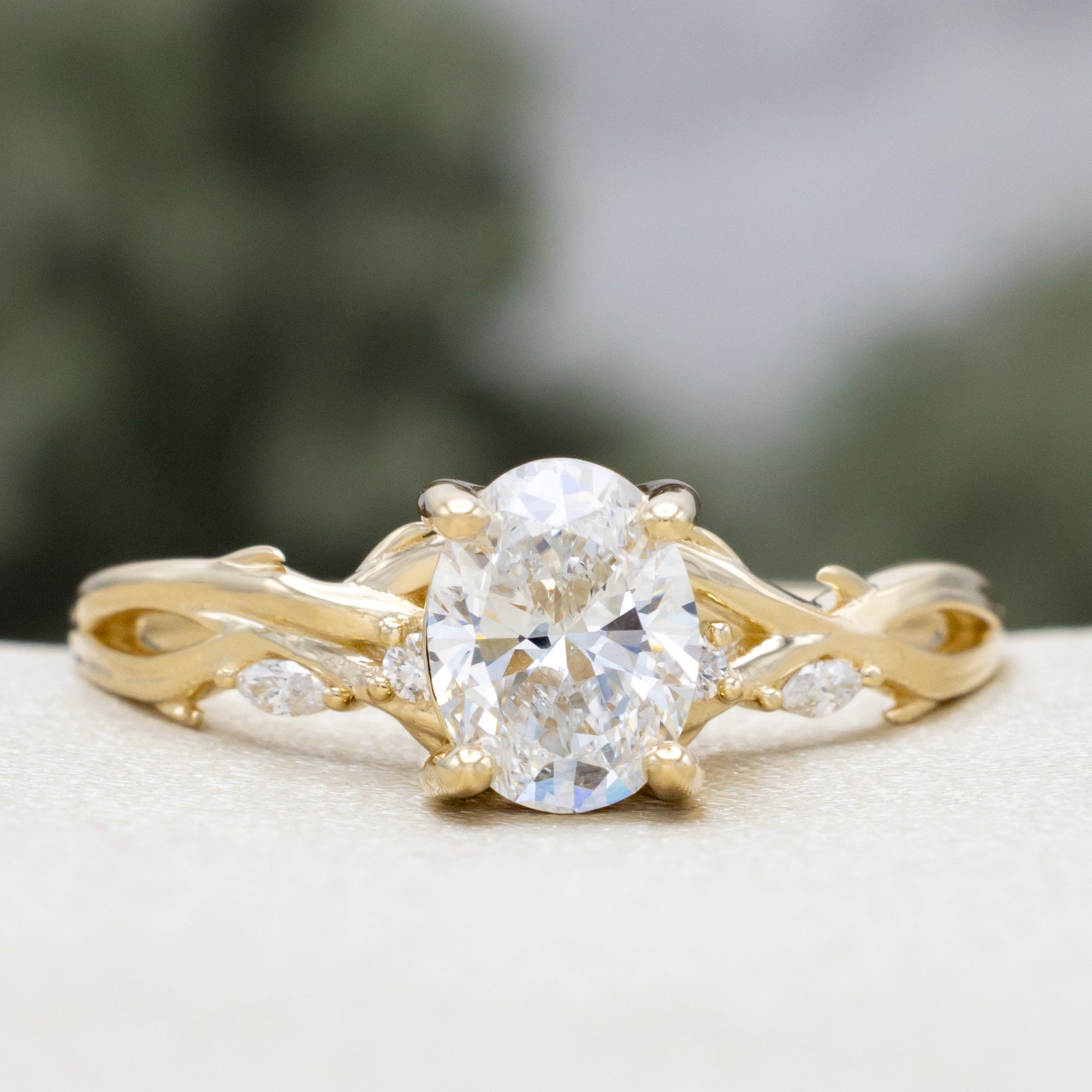 14K gold engagement ring with oval lab-grown diamond and accents against a blurred background