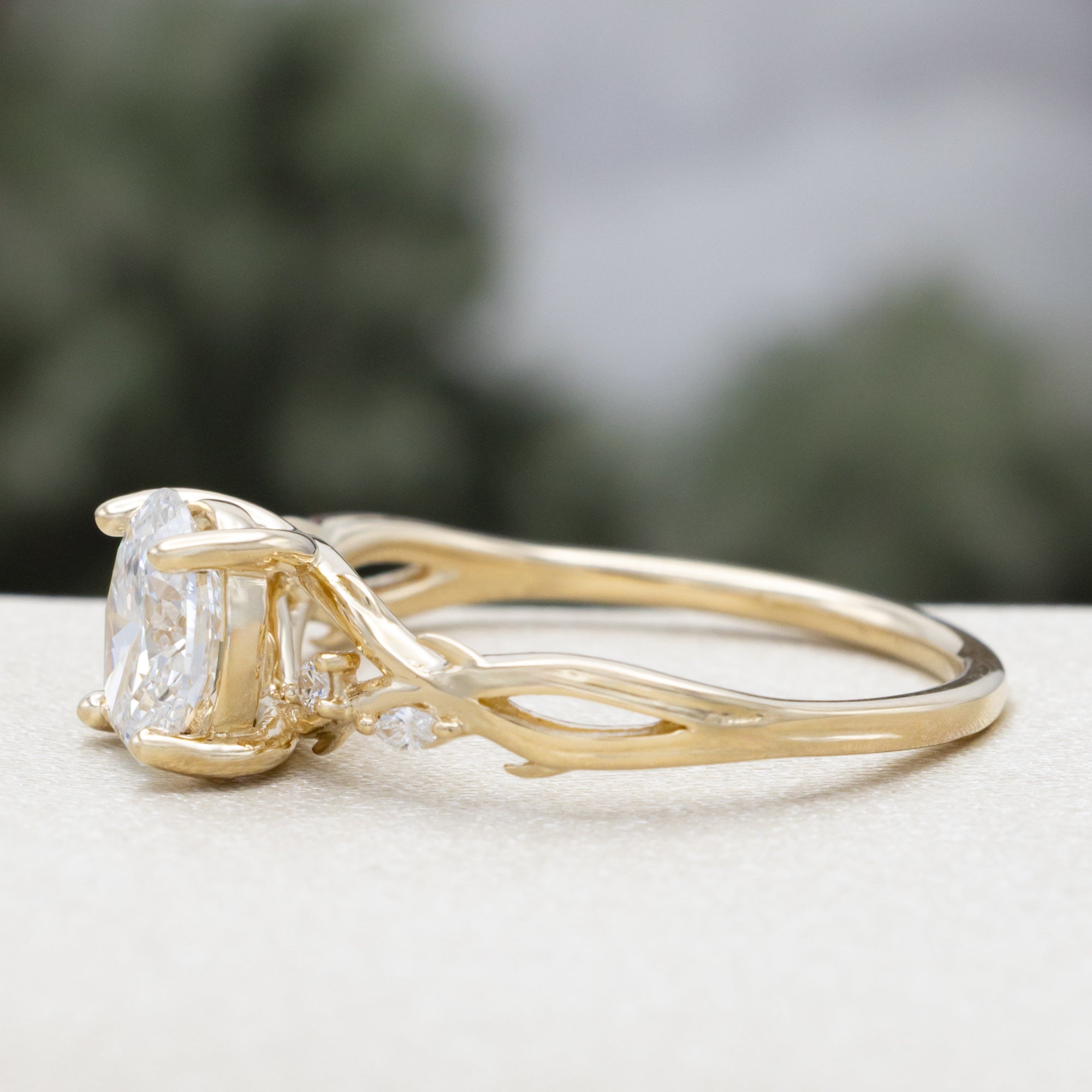 14K gold engagement ring with oval lab-grown diamond and accents against a blurred background