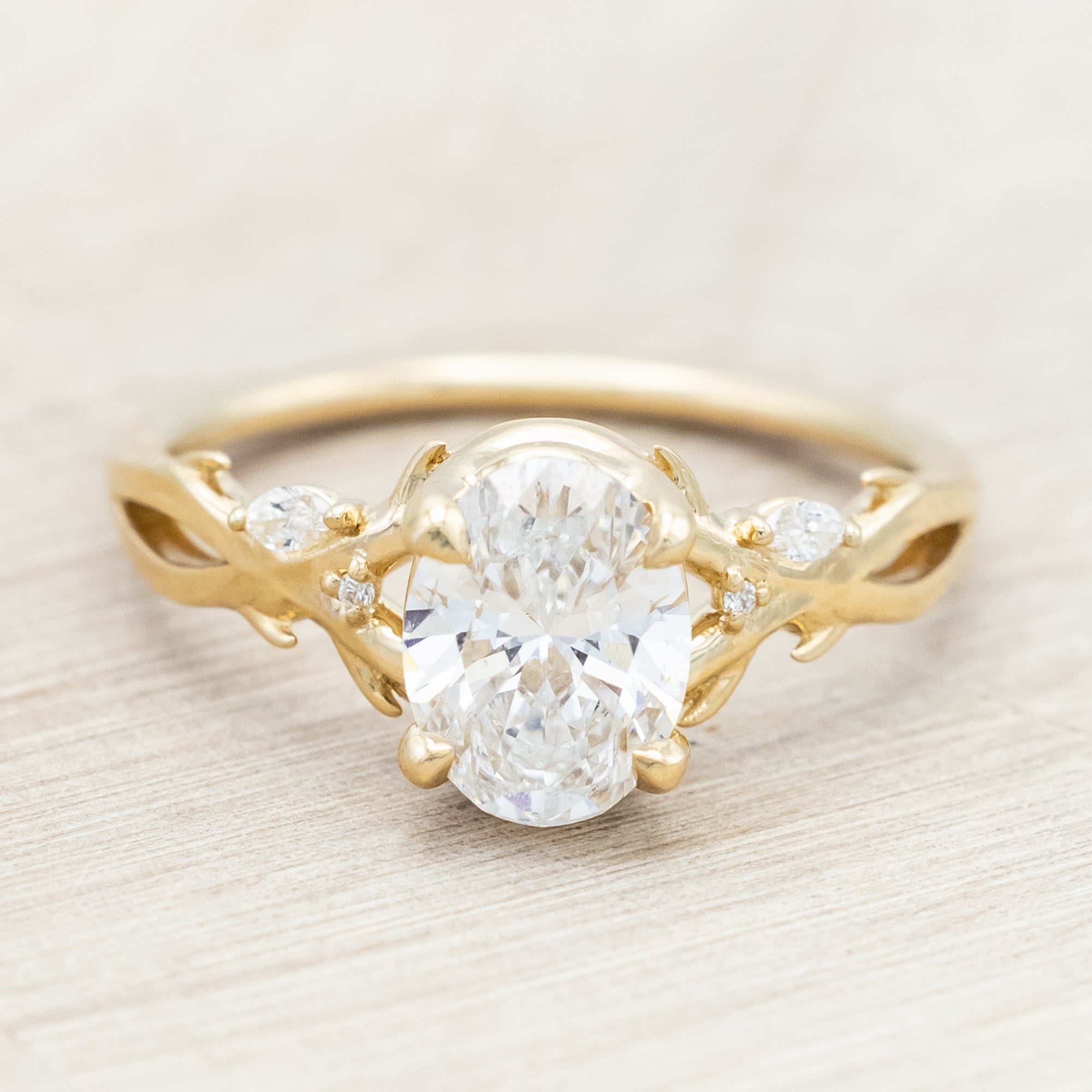 14K gold engagement ring with oval lab-grown diamond and accents against beige background